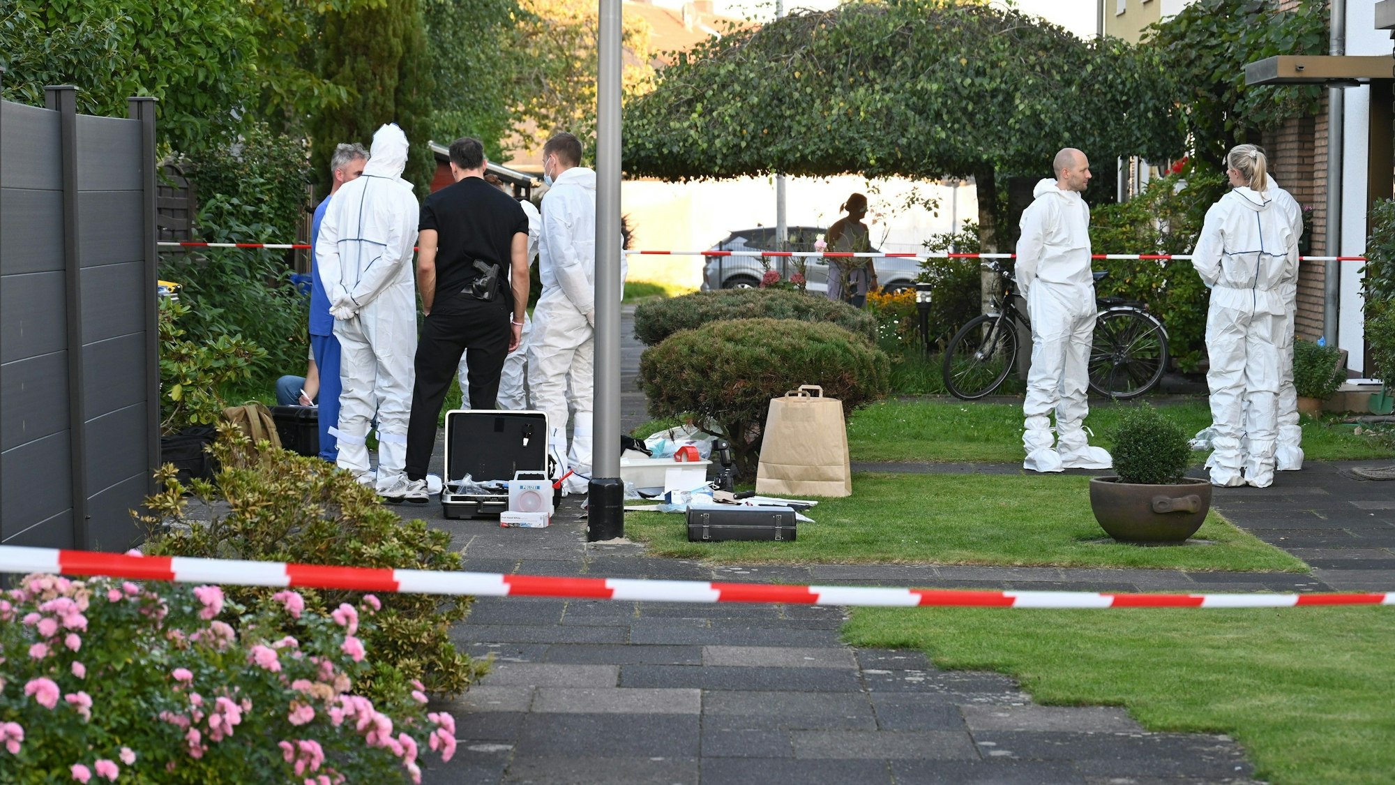 Das Bild zeigt Beamte der Mordkommission in weißen Schutzanzügen.