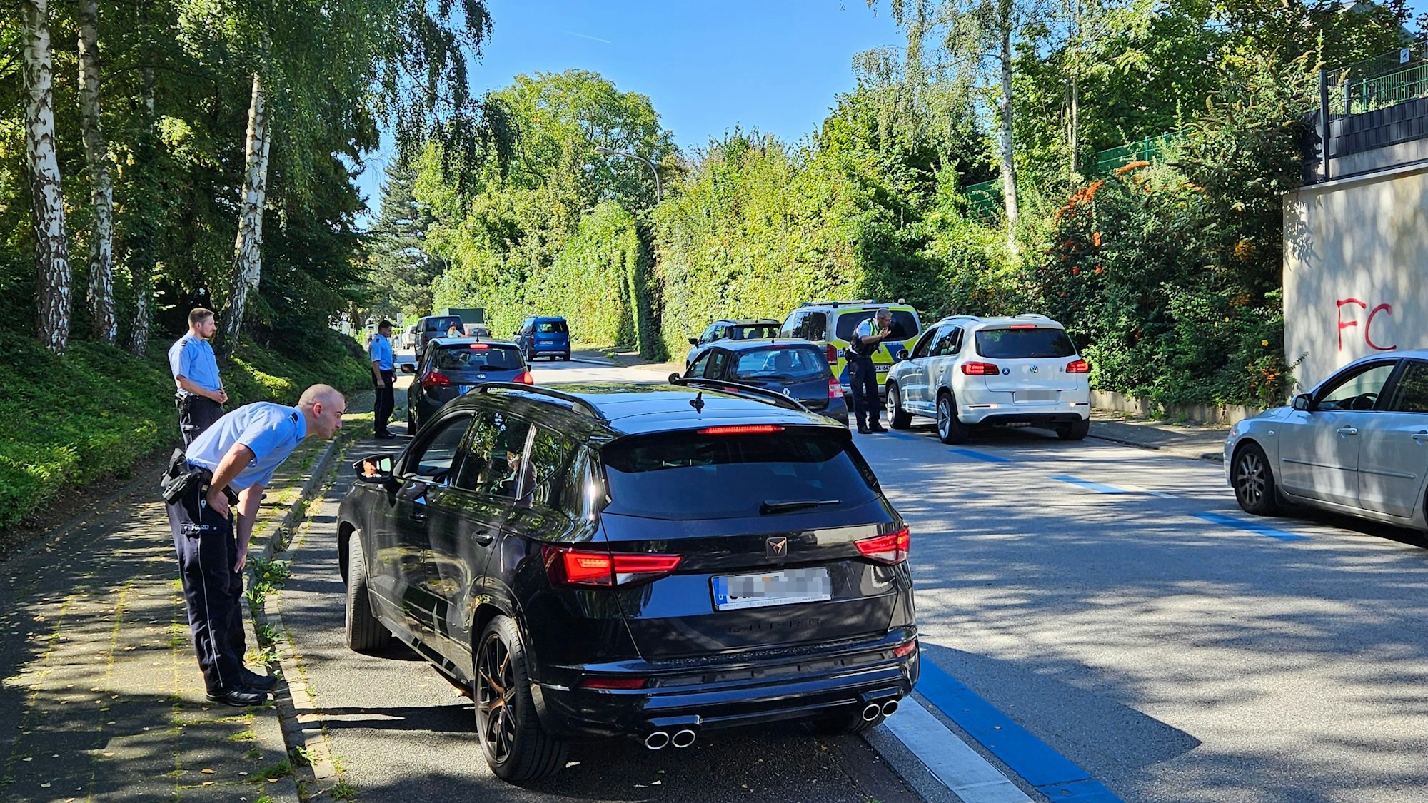 Mehrere uniformierte Polizisten stehen an Autos und sprechen mit den Fahrerinnen und Fahrern.