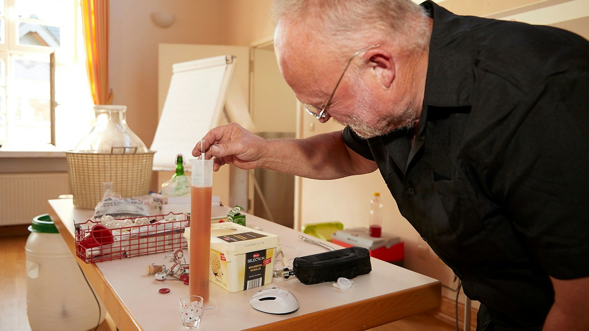Dr. Karl Lindemann taucht den Messtab in ein Reagenzglas mit Most.