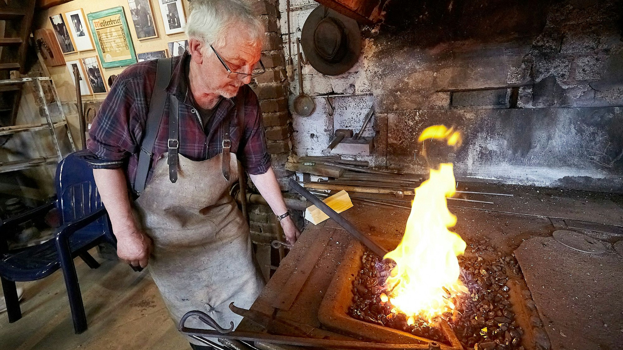 Der Schmied Stefan Pütz steht in einer alten Werkstatt an einem Kohlenfeuer.