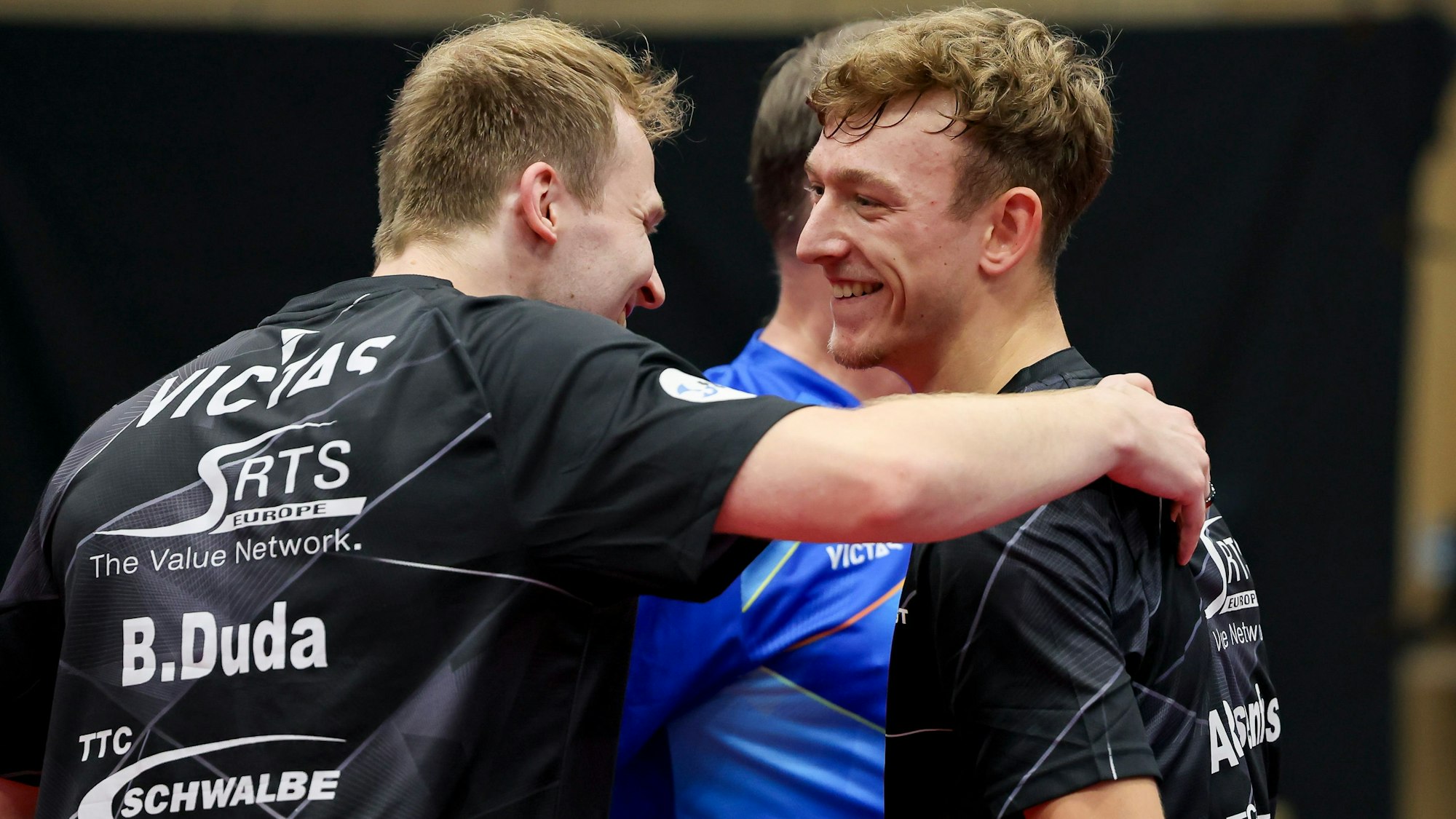 Tischtennis-Spieler Benedikt Duda umarmt seinen Mannschaftskollegen Adrien Rassenfosse.