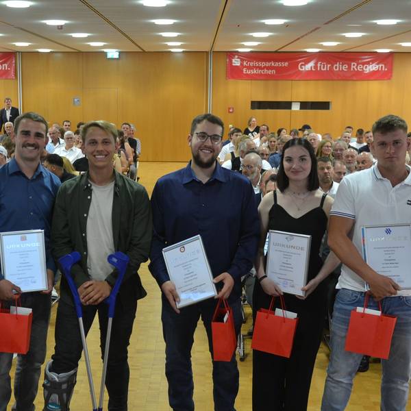Fünf junge Männer und eine Frau stehen in einem großen Saal und halten eine Urkunde in den Händen. Im Hintergrund ist Publikum zu erkennen.