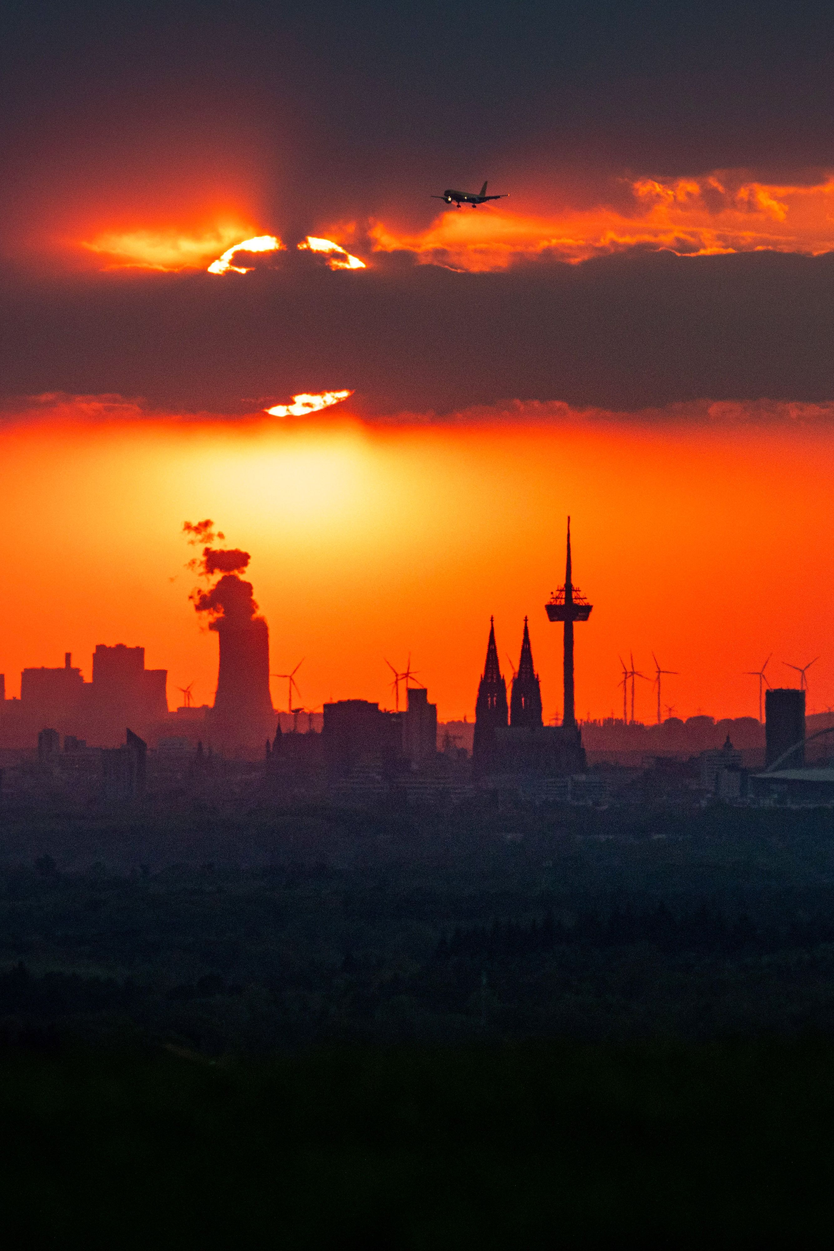 Die Sonne steht am Abend kurz vor Sonneuntergang hinter Wolken über der Stadt. (Symbolbild)