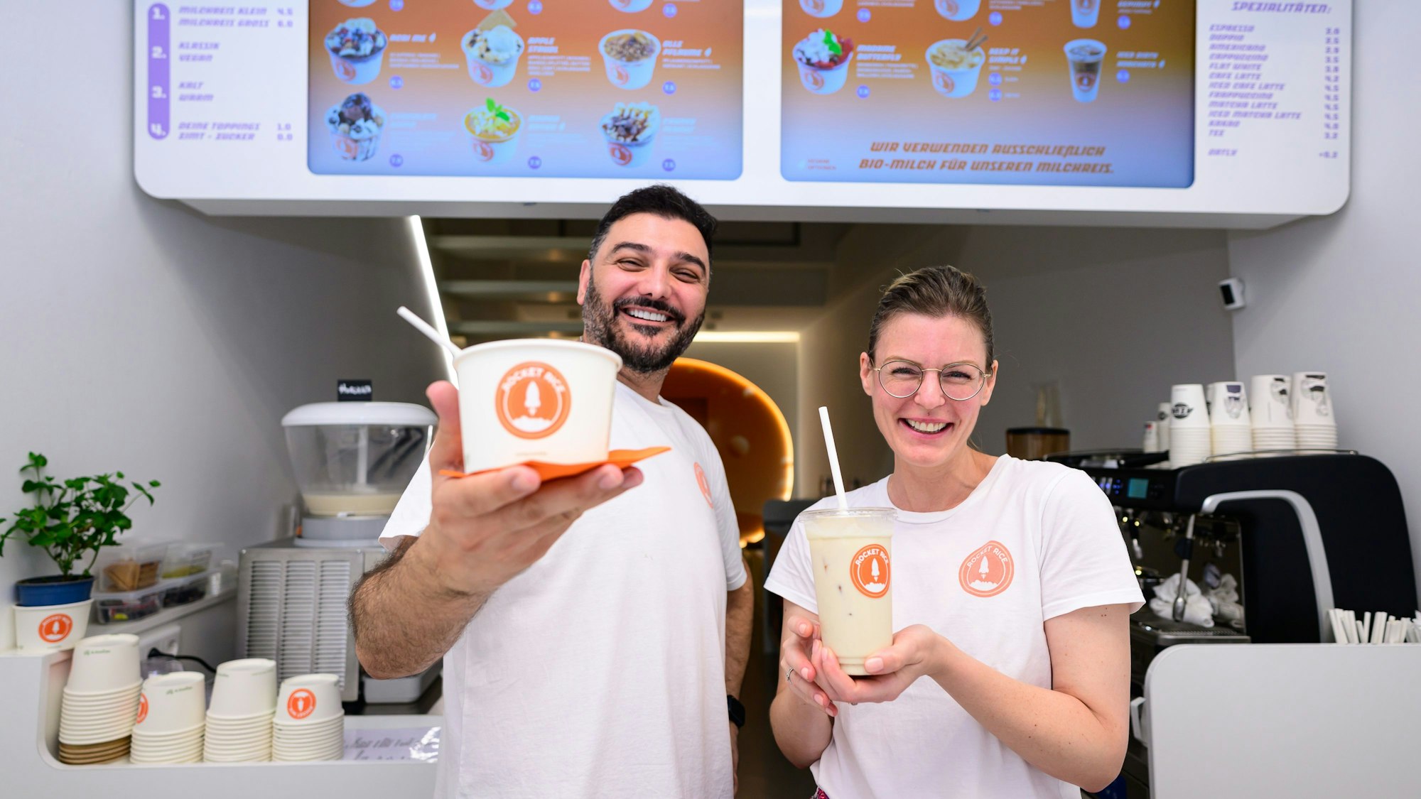 Geschäftsführerin Maria-Carina Spanier und ihr Partner Volkan Gerdan posieren mit Milchreis im Becher.