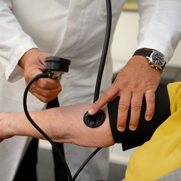 Ein Hausarzt misst einer Patientin den Blutdruck.