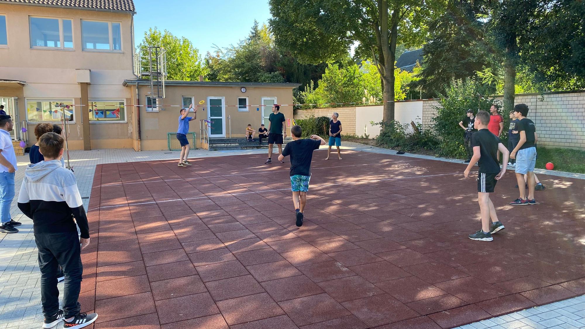 Jugendliche spielen auf einem Tartanfeld Volleyball.