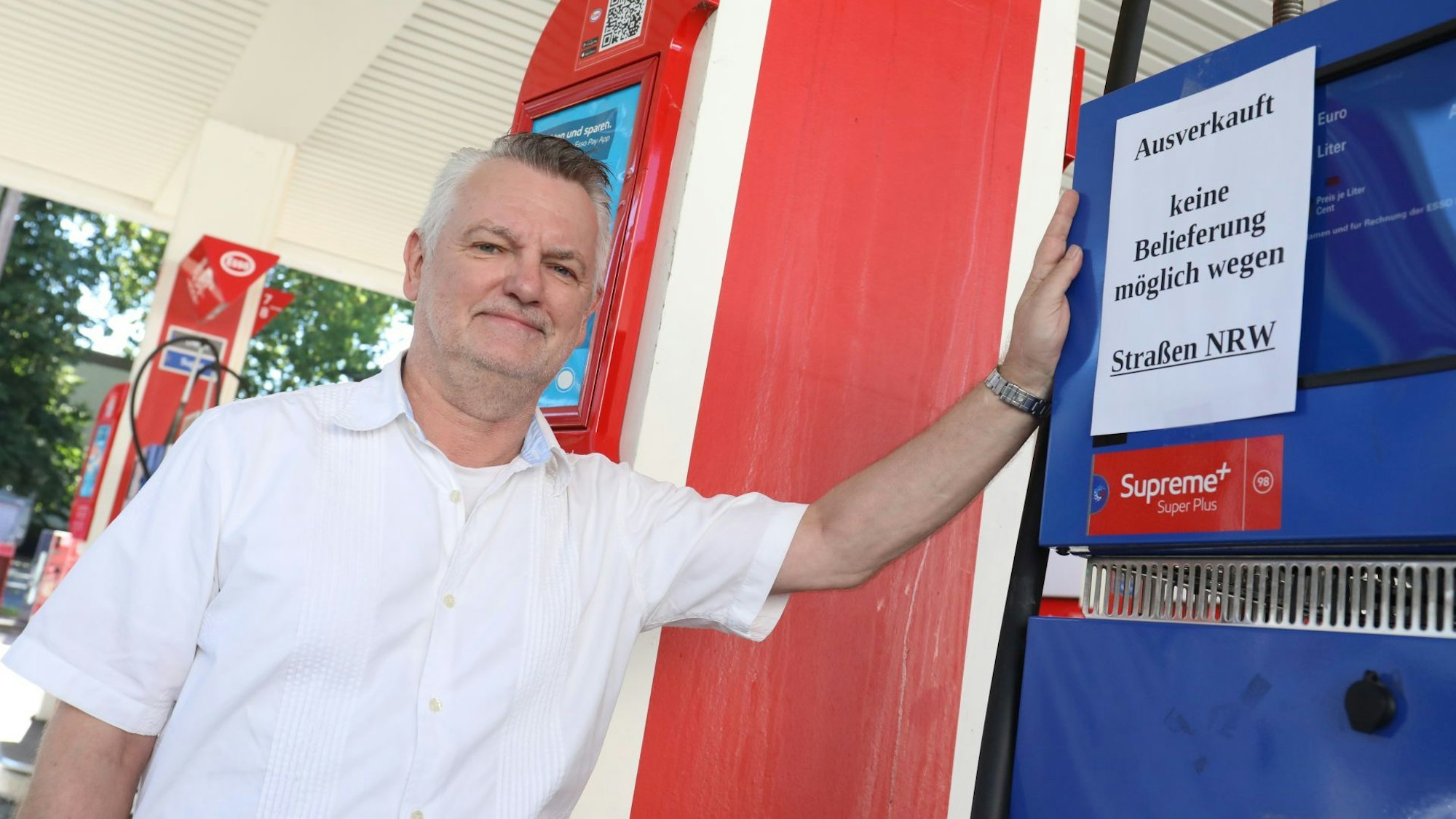 Ein Mann steht an einer Zapfsäule, an der ein Schild hängt mit der Aufschrift „Ausverkauft. Keine Belieferung möglich wegen Straßen NRW“.