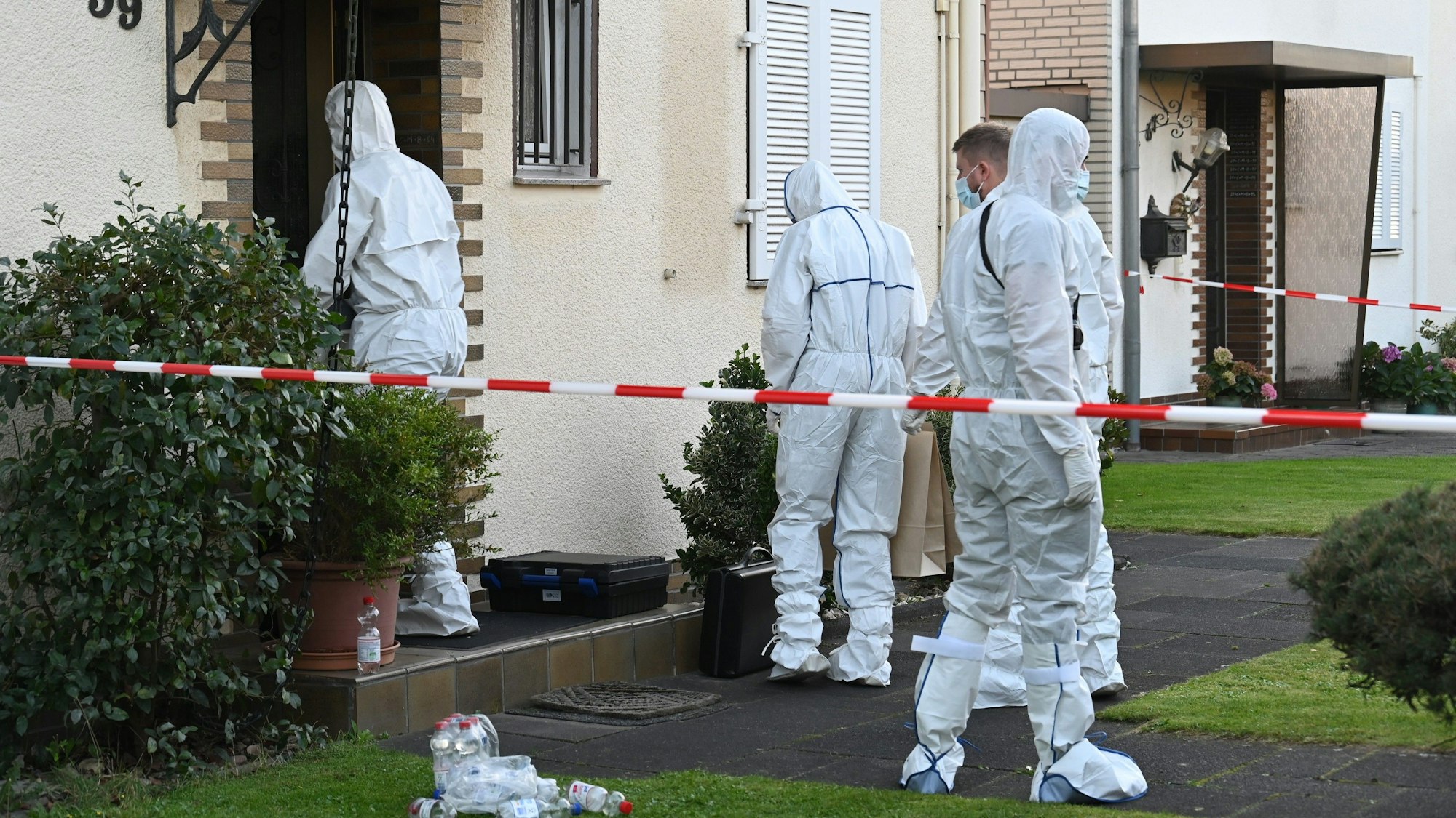 Das Bild zeigt Kripobeamte in weißen Schutzanzügen vor dem Haus des Rentners.