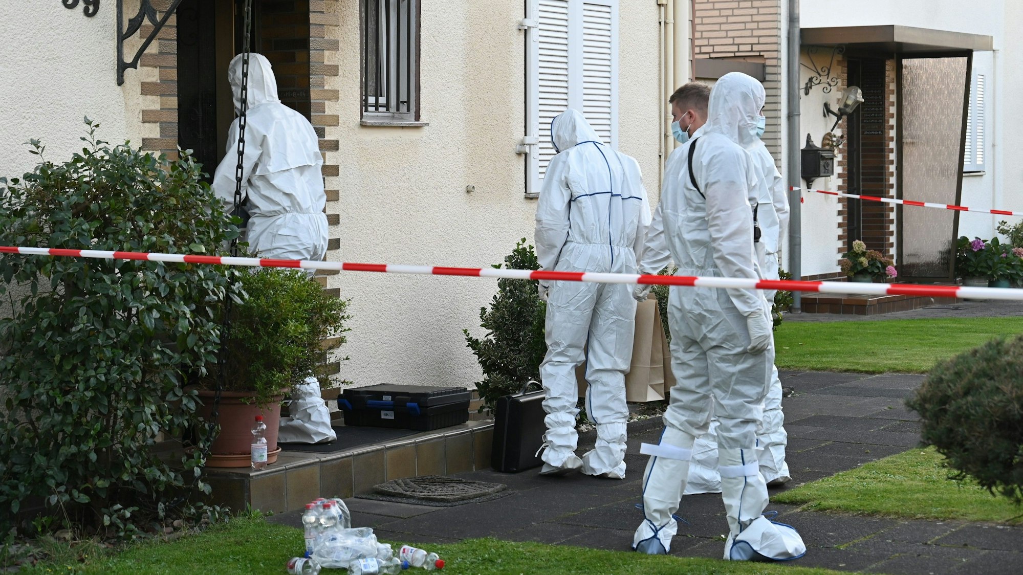 Das Bild zeigt mehrere Kripobeamte in weißen Schutzanzügen vor dem Haus des verstorbenen Rentners.