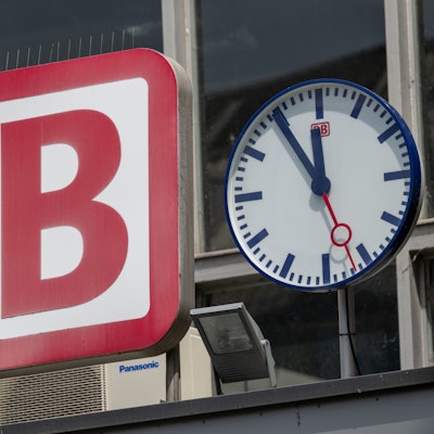 Die Uhr neben dem Logo der Deutschen Bahn (DB) zeigt am Eingang zum Münchner Hauptbahnhof auf „Fünf vor Zwölf“. (Symbolbild)