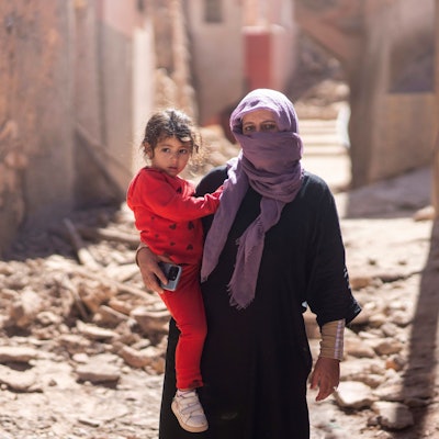 Eine Frau steht mit ihrer Tochter nach dem verheerenden Erdbeben in Marokko in der Hauptstadt Marrakesch auf einer Straße, die von Trümmerteilen übersät ist.