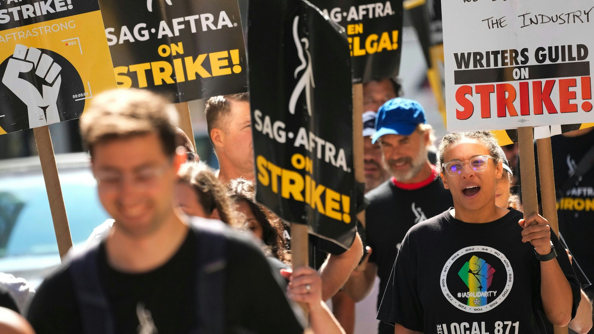 18.08.2023, USA, New York: Streikende gehen vor den Büros von Warner Bros., Discovery und Netflix in Manhattan. Seit über vier Monaten streiken in Hollywood die Drehbuchautoren - und gehen mit Schildern und Sprechchören auf die Straße. Mitte Juli schlossen sich Schauspielerinnen und Schauspieler den Schreibern an. (zu dpa "Doppelstreik in Hollywood - Kein Ende in Sicht") Foto: Mary Altaffer/AP +++ dpa-Bildfunk +++