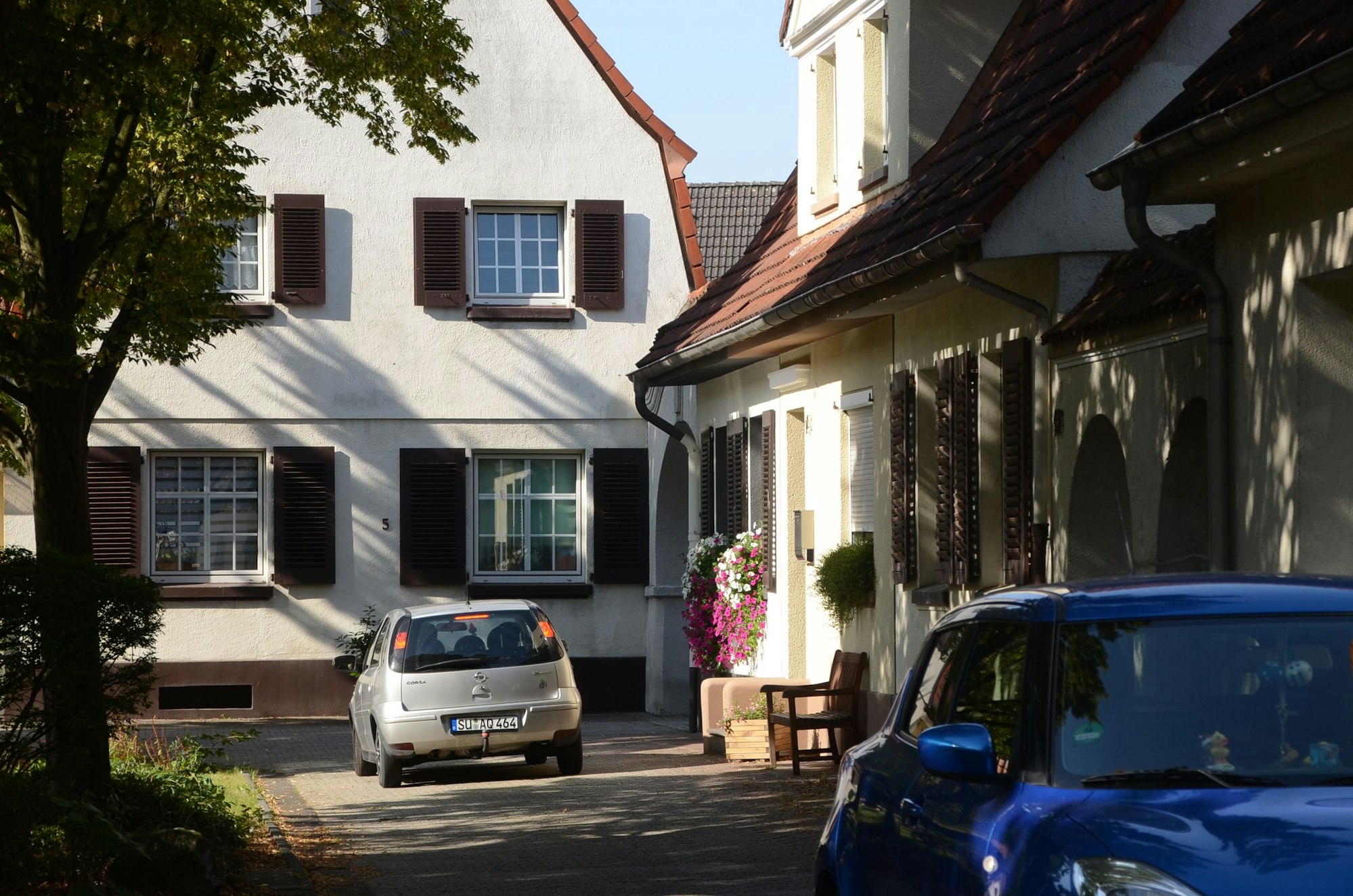 Häuser einer Arbeitersiedlung. Die Häuser sind kleine, haben Fenster mit Sprossen und Klappläden. Die Dächer sind rot gedeckt.
