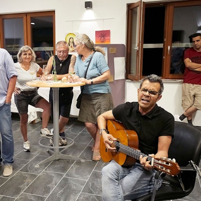 Ahmad Abbaspour singt und spielt Gitarre. Einige Zuhörer stehen um ihn herum.