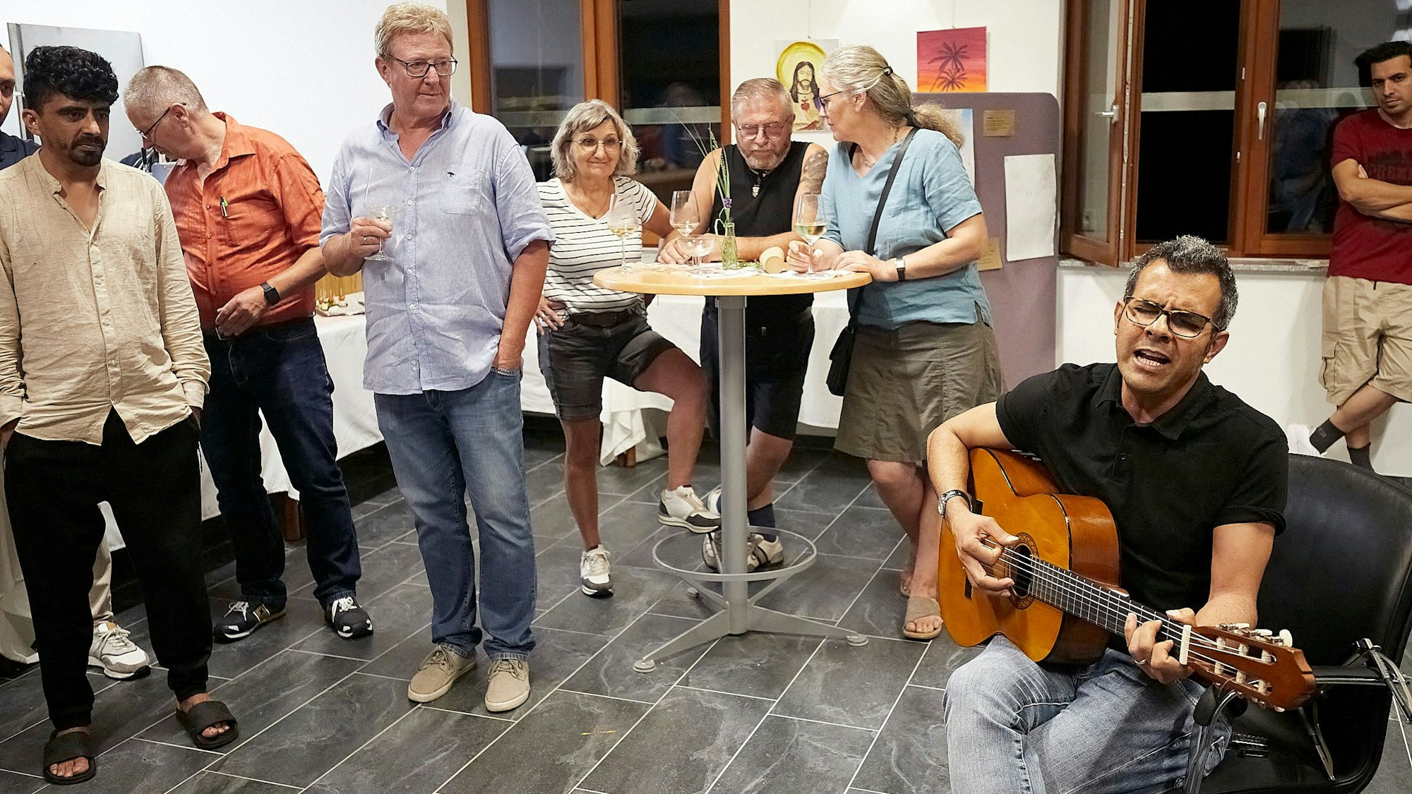 Ahmad Abbaspour singt und spielt Gitarre. Einige Zuhörer stehen um ihn herum.