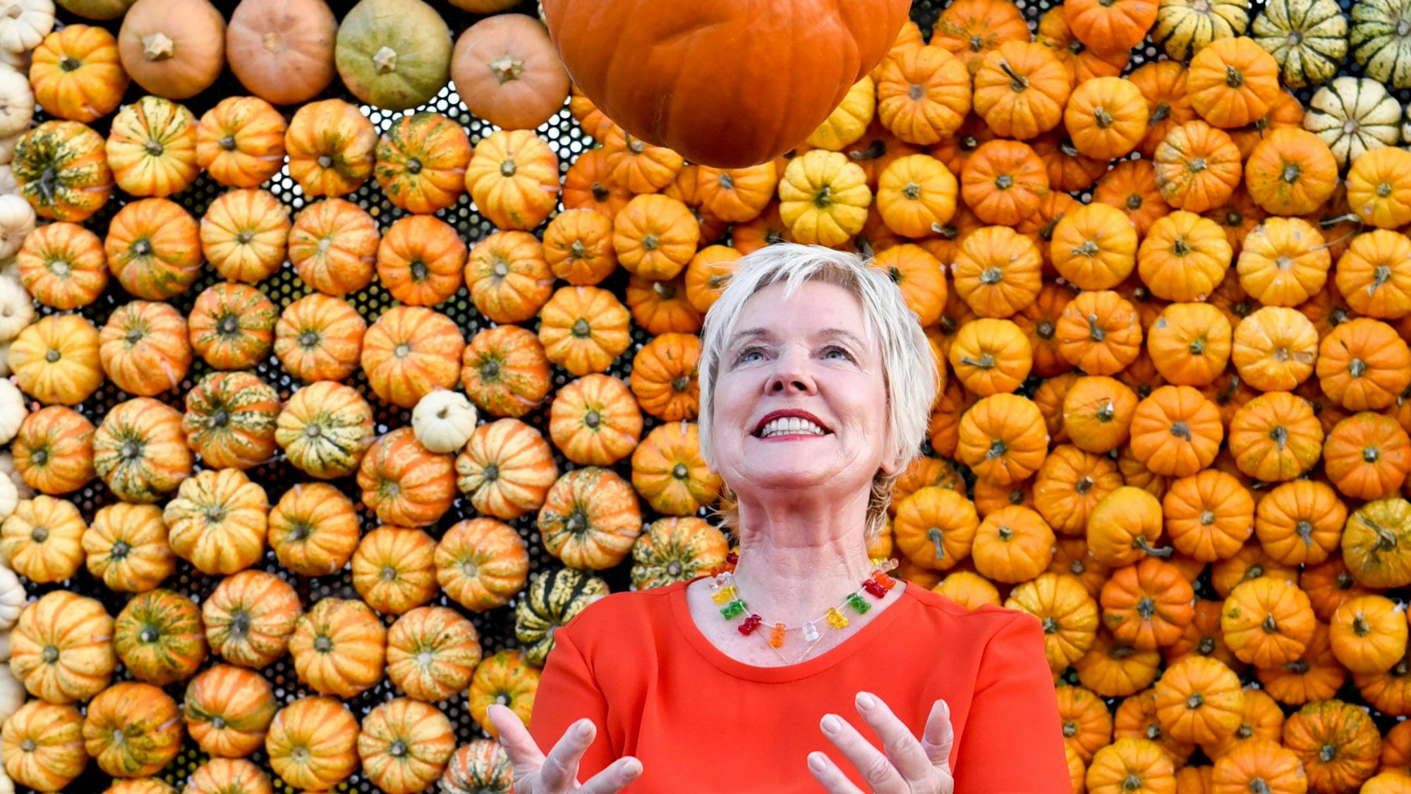 Eine Frau wirft einen Kürbis hoch.