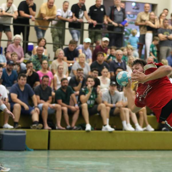 Ein Handballspieler liegt fast quer in der Luft.