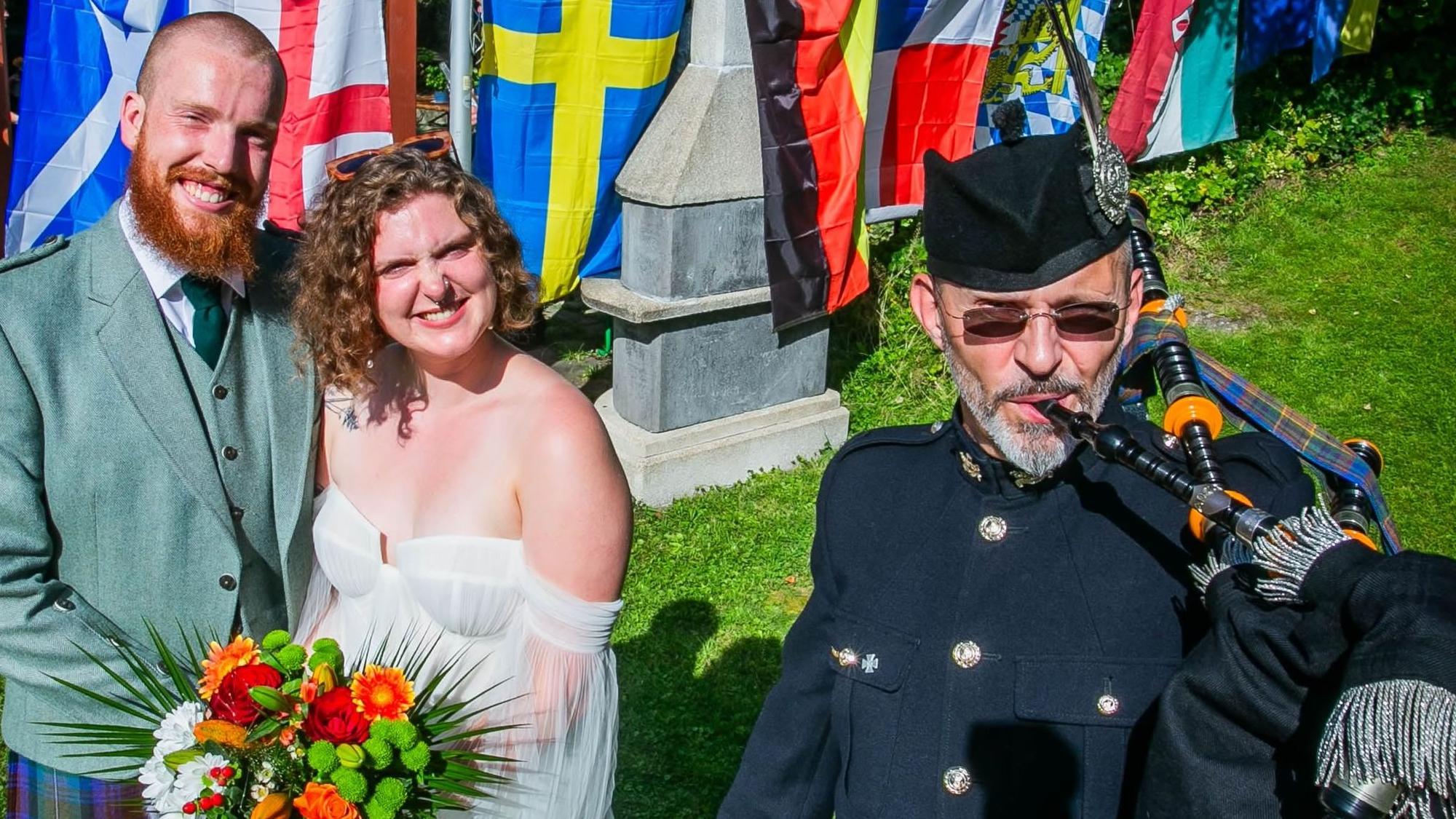 Mit Musik von Dudelsackspieler Michael Hoffmann von der Gruppe „Call of Pipes“ aus Waldbröl feiert das schottische Paar Nils und Anna Fritsch am Samstagnachmittag in Wiehl-Merkausen und im Kreise der weitverzweigten Familie noch einmal Hochzeit. Hier steht das Paar vor den Fahnen der beteiligten Nationen.