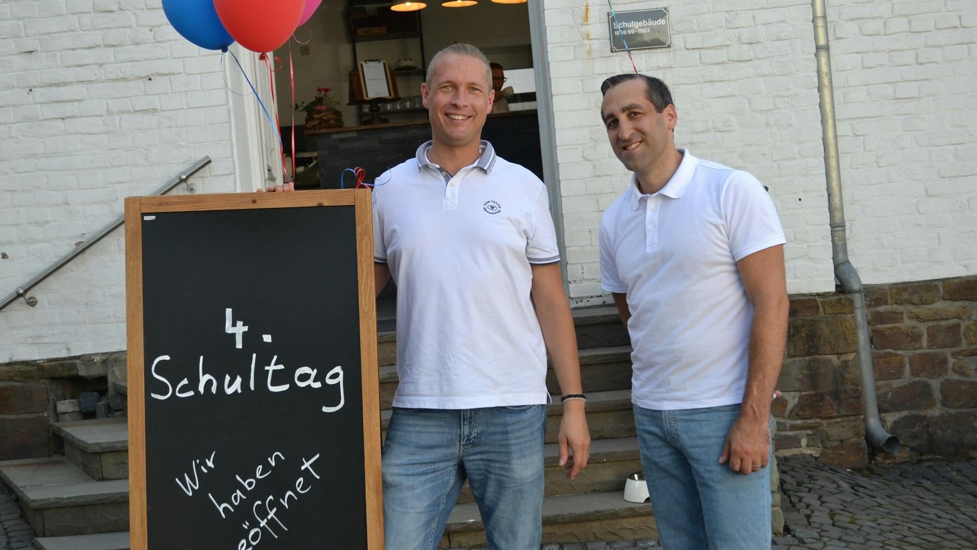 Zwei Männer stehen vor einem Café.
