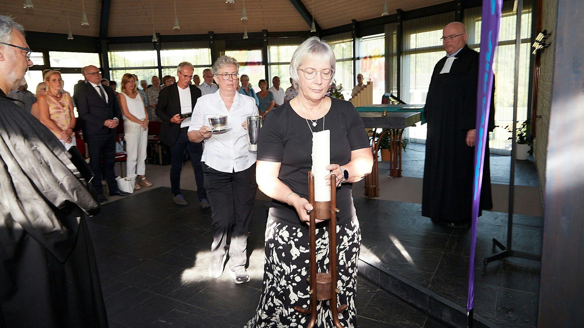 Die Presbyter tragen Gottesdienstutensilien wie Kerze oder Gefäße in die Sakristei. Vorne Gabriele Leufgen, dahinter Brigitte Weber und Roland Reddelien