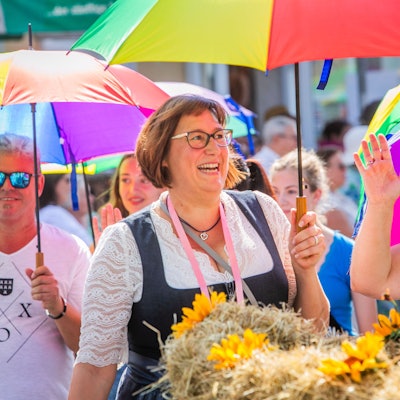 Teilnehmerinnen und Teilnehmer des Erntezugs mit bunten Regenschirmen