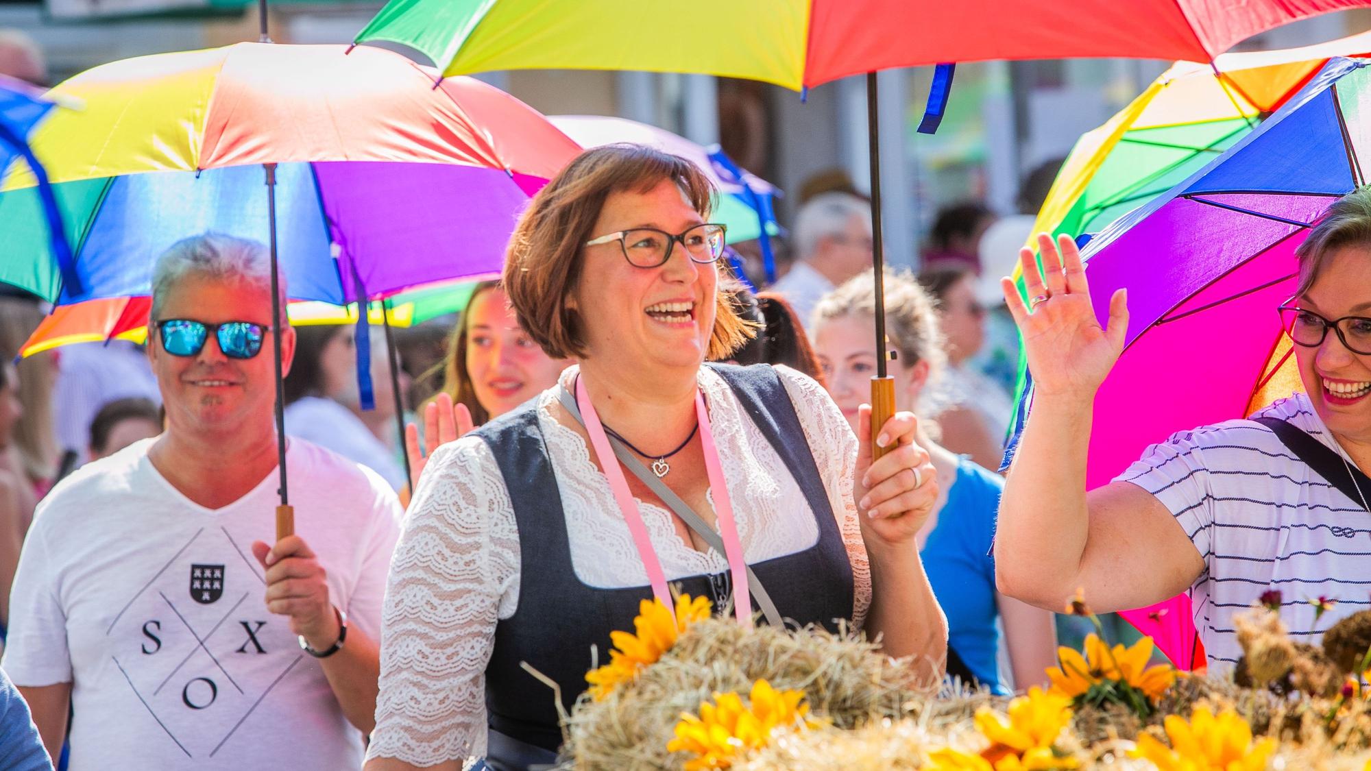 Teilnehmerinnen und Teilnehmer des Erntezugs mit bunten Regenschirmen