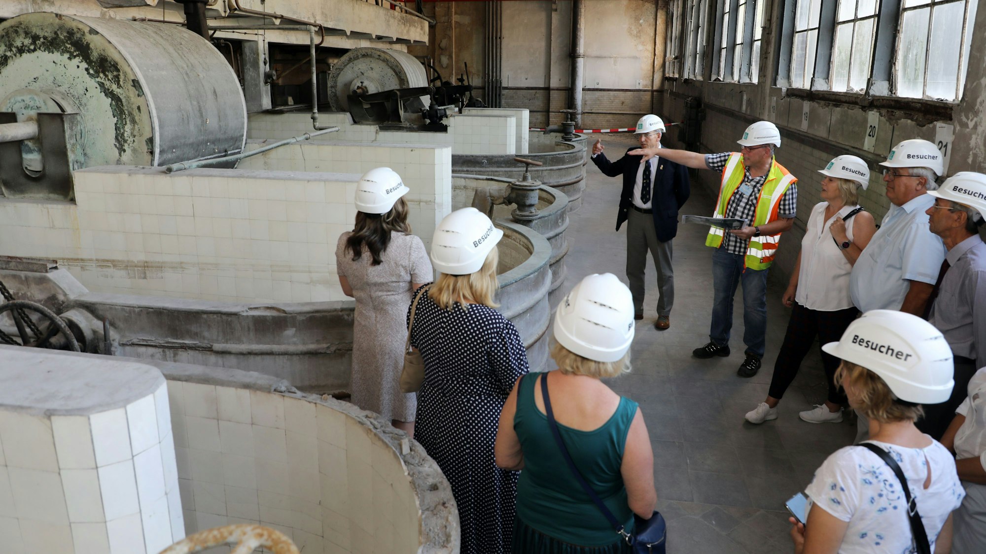 Ein Mitarbeitender der Stadt führt eine Gruppe durch eine ehemalige Fabrikhalle von Zanders.