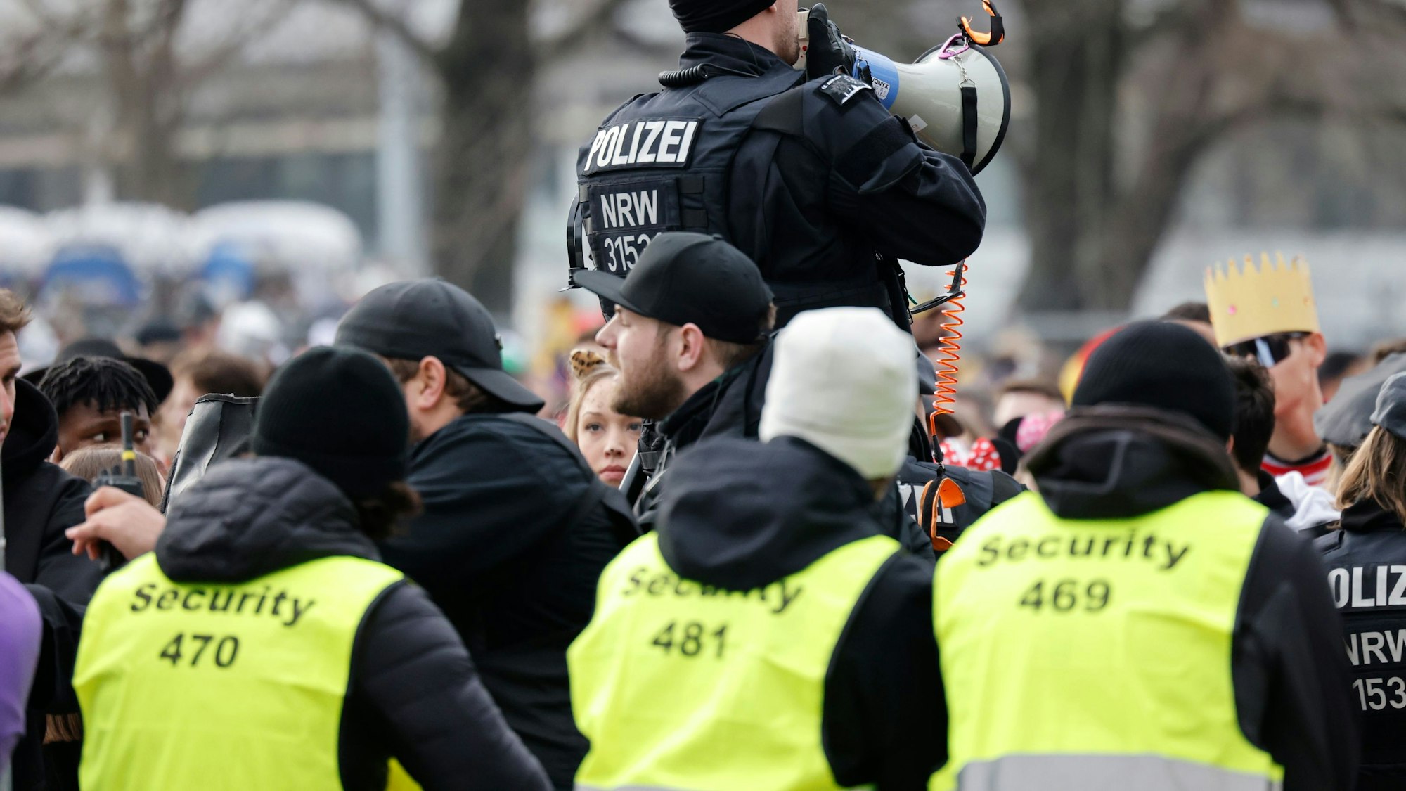 Drei Mitarbeiter von Sicherheitsfirmen und ein Polizist auf der Zülpicher Straße.