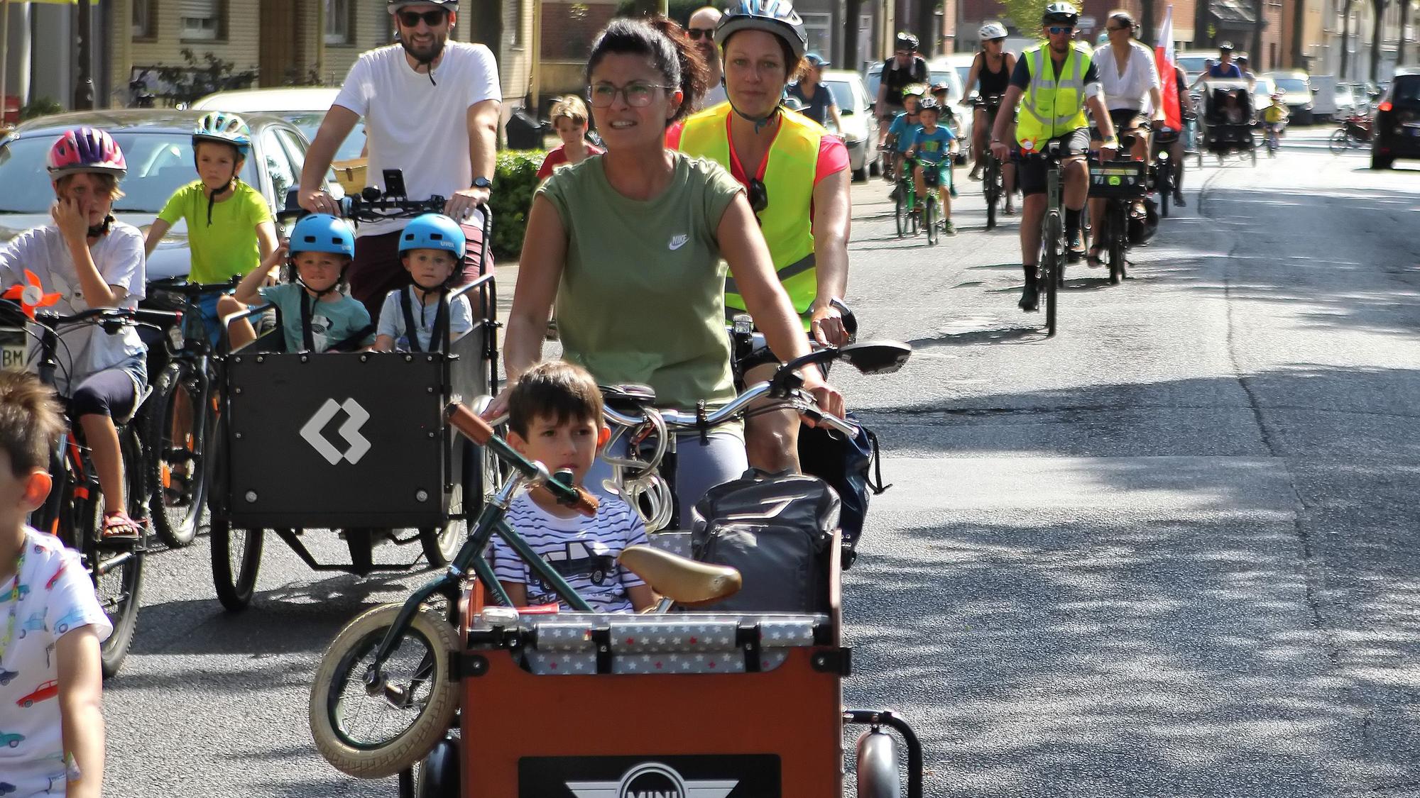 Zu sehen sind einige Radfahrer, die mit ihren Lastenrädern und Drahteseln eine Straße entlang fahren.