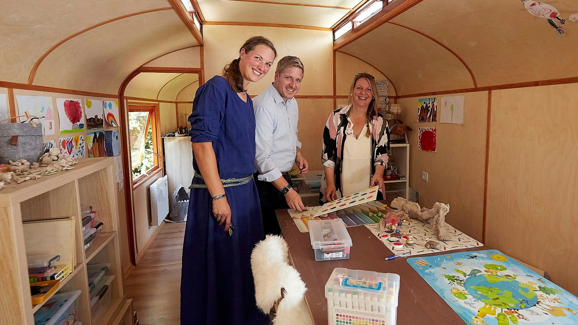 Landrat Markus Ramers, Rebecca Müller (links) und Klaudia Skodnik stehen in einem Bauwagen, der Spielmaterial und die Möglichkeit für Kreativangebote bietet.