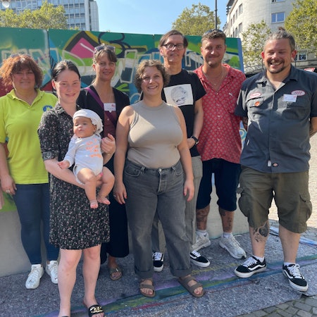 Alle stehen vor einer bunten Graffitiwand.