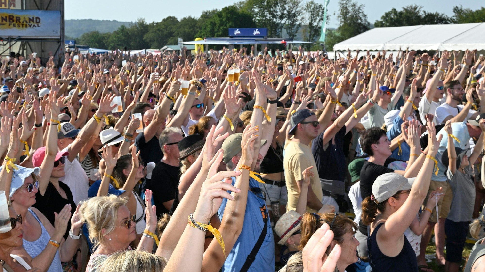 Menschen strecken beim Freiluft-Festival „Rheinbrand“ die Hände in die Höhe.