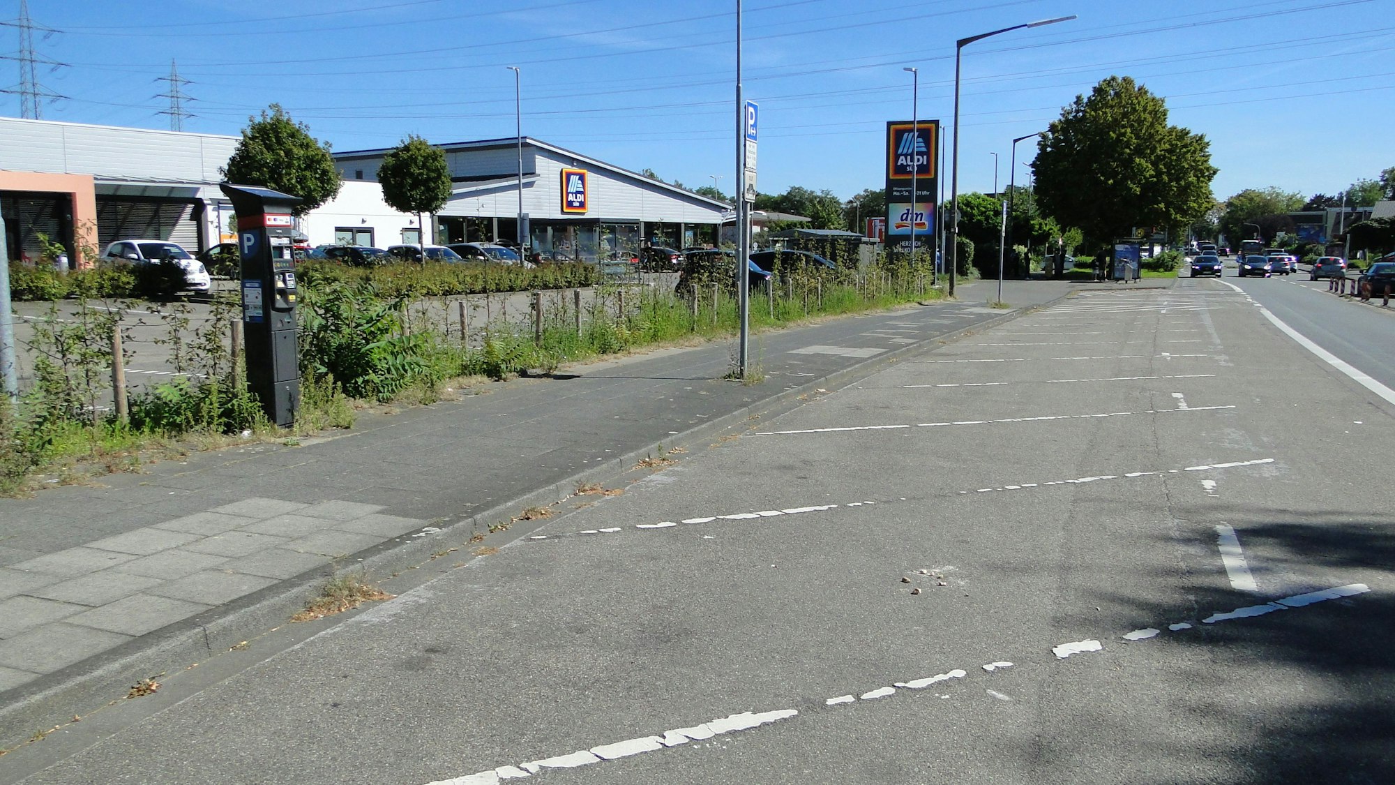 Eine Straße mit leeren Parkplätzen und einem Parkautomaten ist zu sehen.