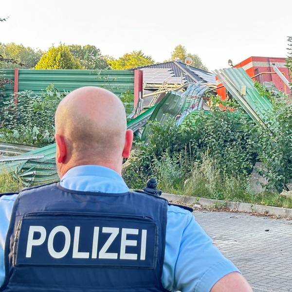Ein Polizist steht vor der Lok eines entgleisten Güterzuges.