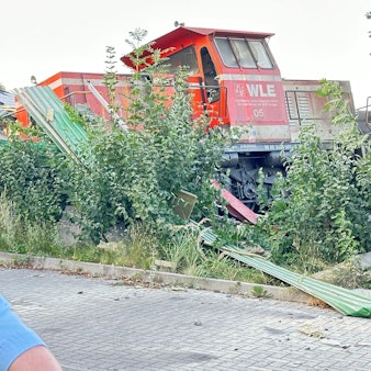 Ein Polizist steht vor der Lok eines entgleisten Güterzuges.