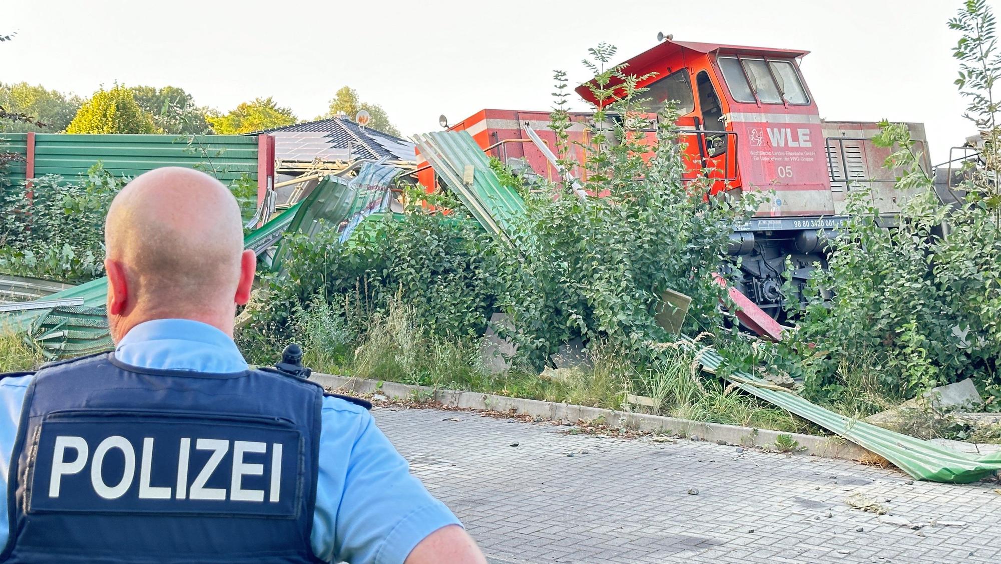 Ein Polizist steht vor der Lok eines entgleisten Güterzuges.
