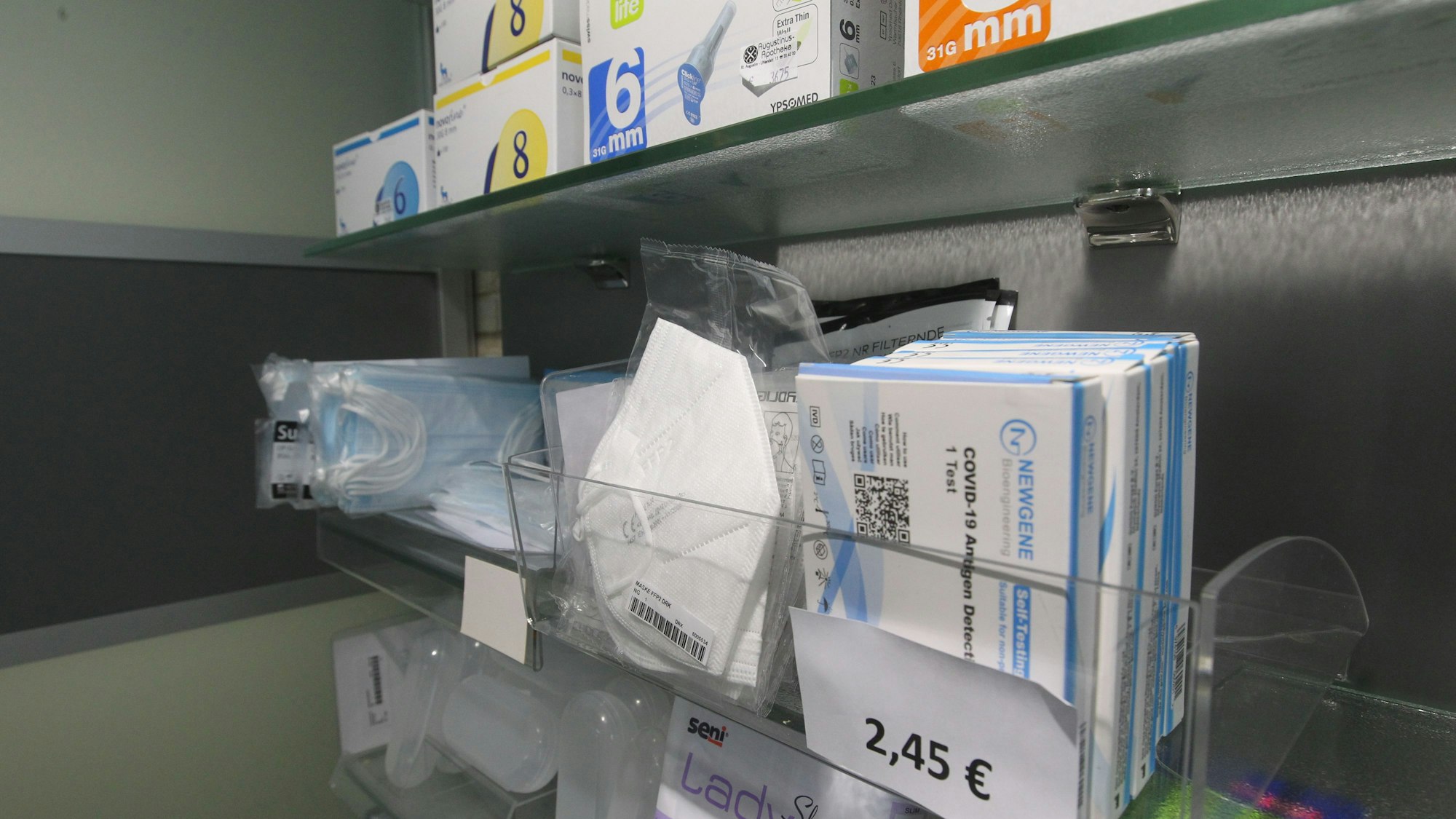 Masken und Corona-Tests in einem Regal.