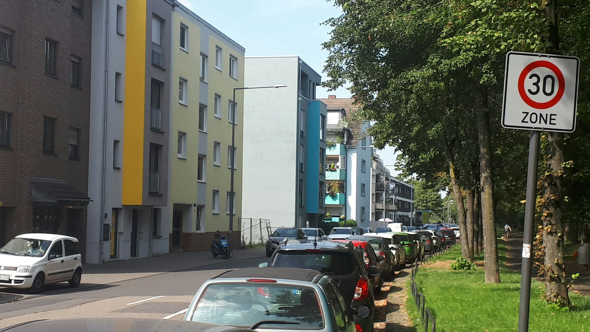 EinTempo-30-Schild steht am Rande einer Straße, auf der viele Autos parken.