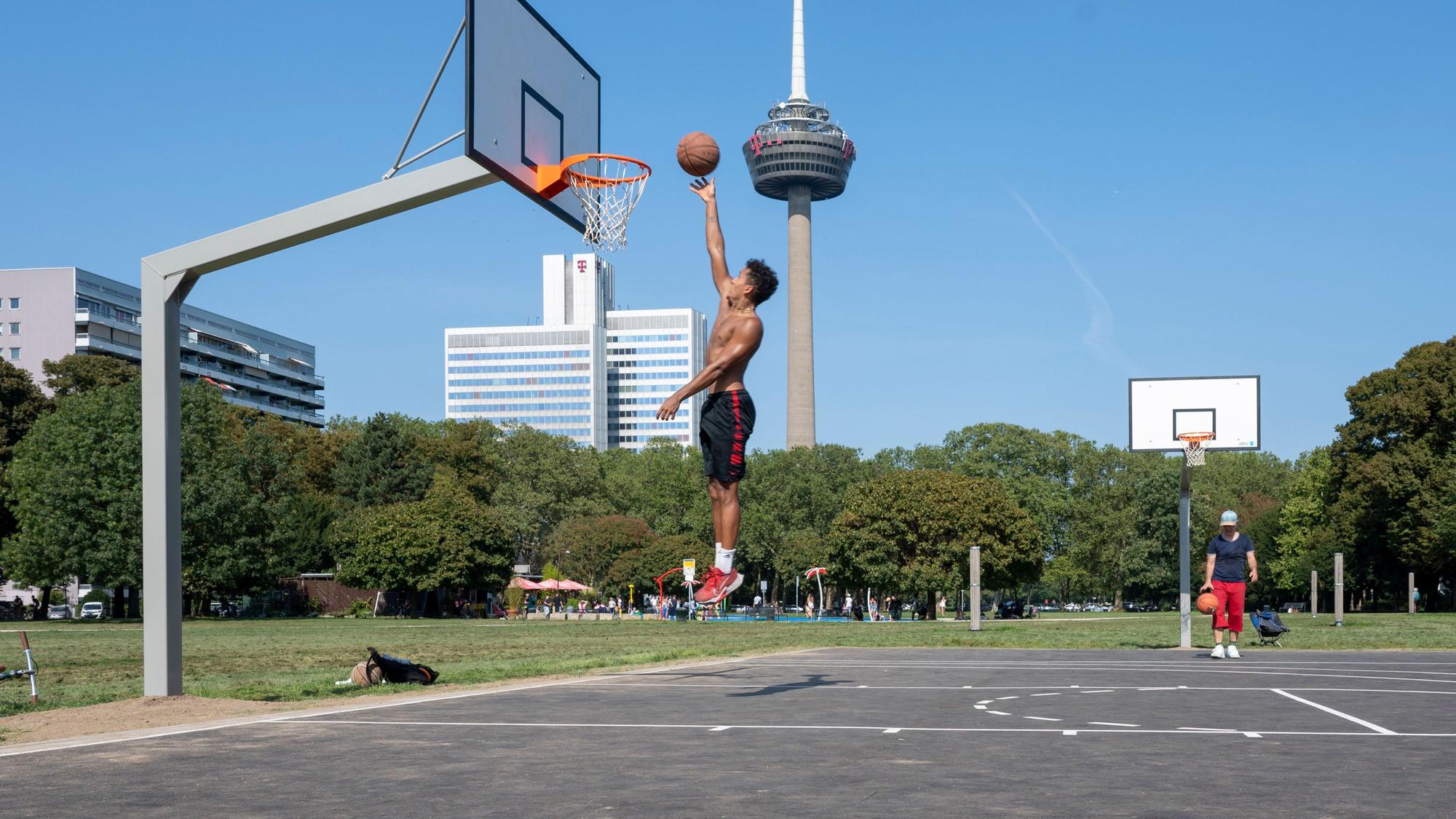 Im Grüngürtel wird Basketball gespielt und auf den Korb gezielt.