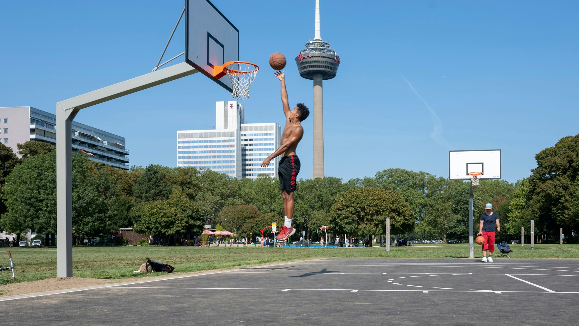 Im Grüngürtel wird Basketball gespielt und auf den Korb gezielt.