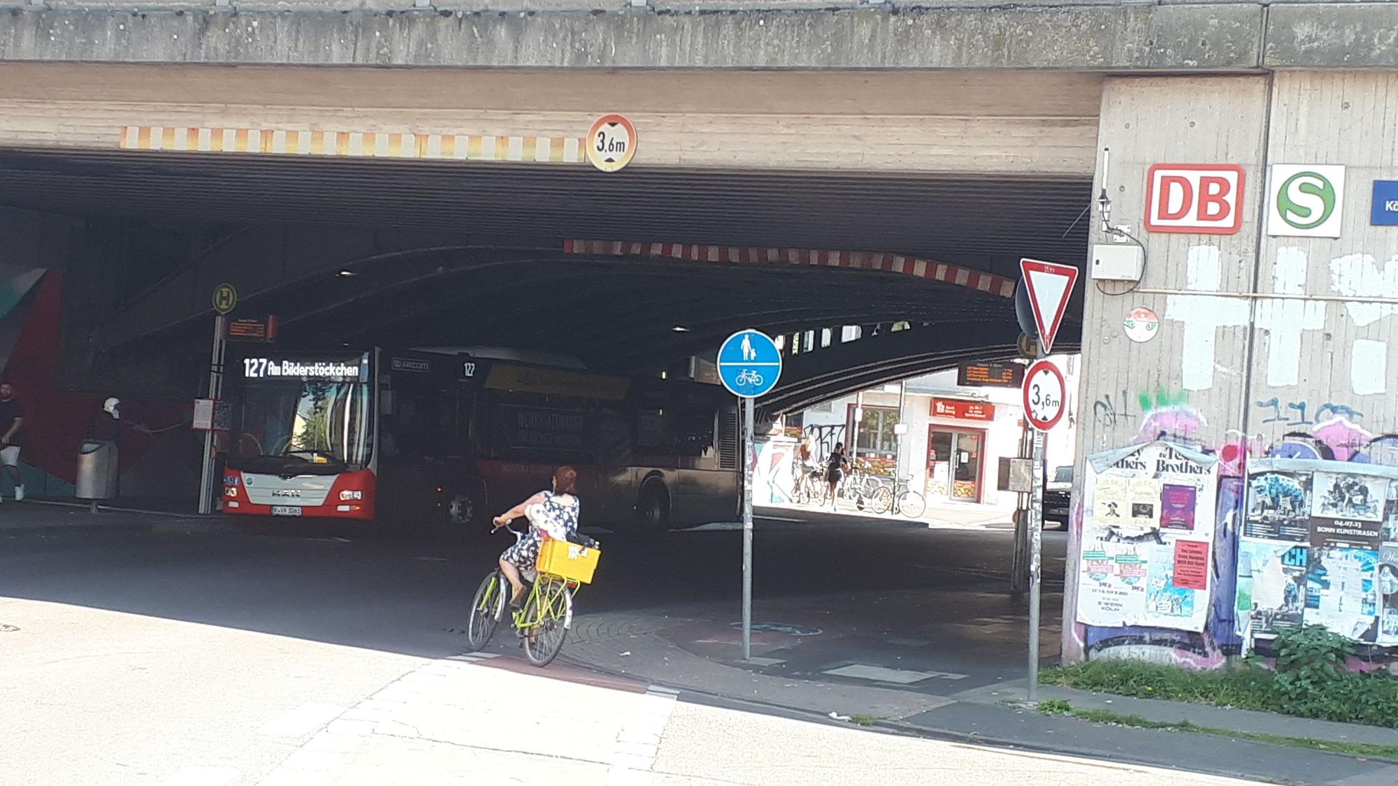 Eine Radfahrerin biegt in einen Tunnel, ein Bus steht schon dort an einer Haltestelle.