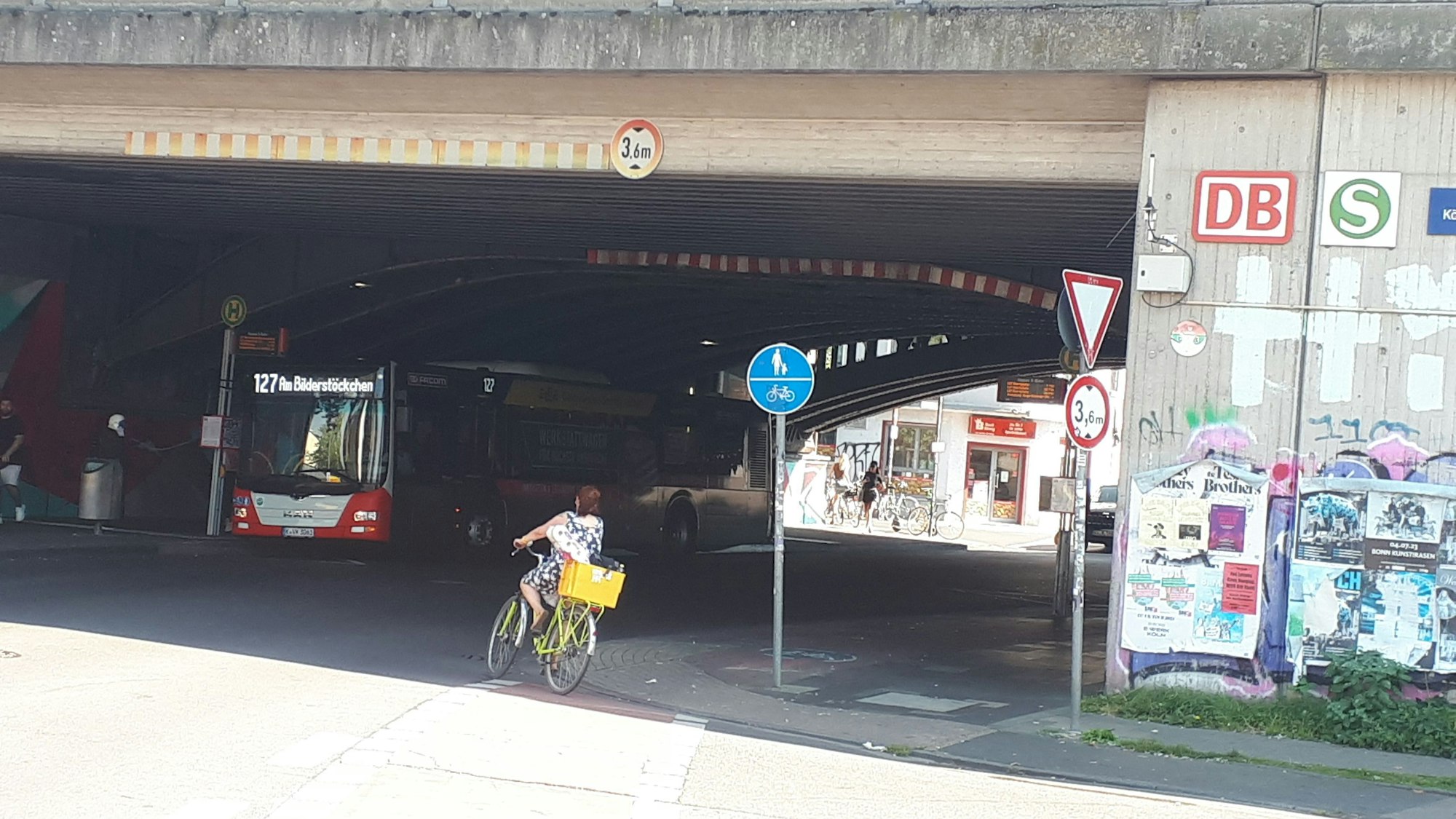 Eine Radfahrerin biegt in einen Tunnel, ein Bus steht schon dort an einer Haltestelle.