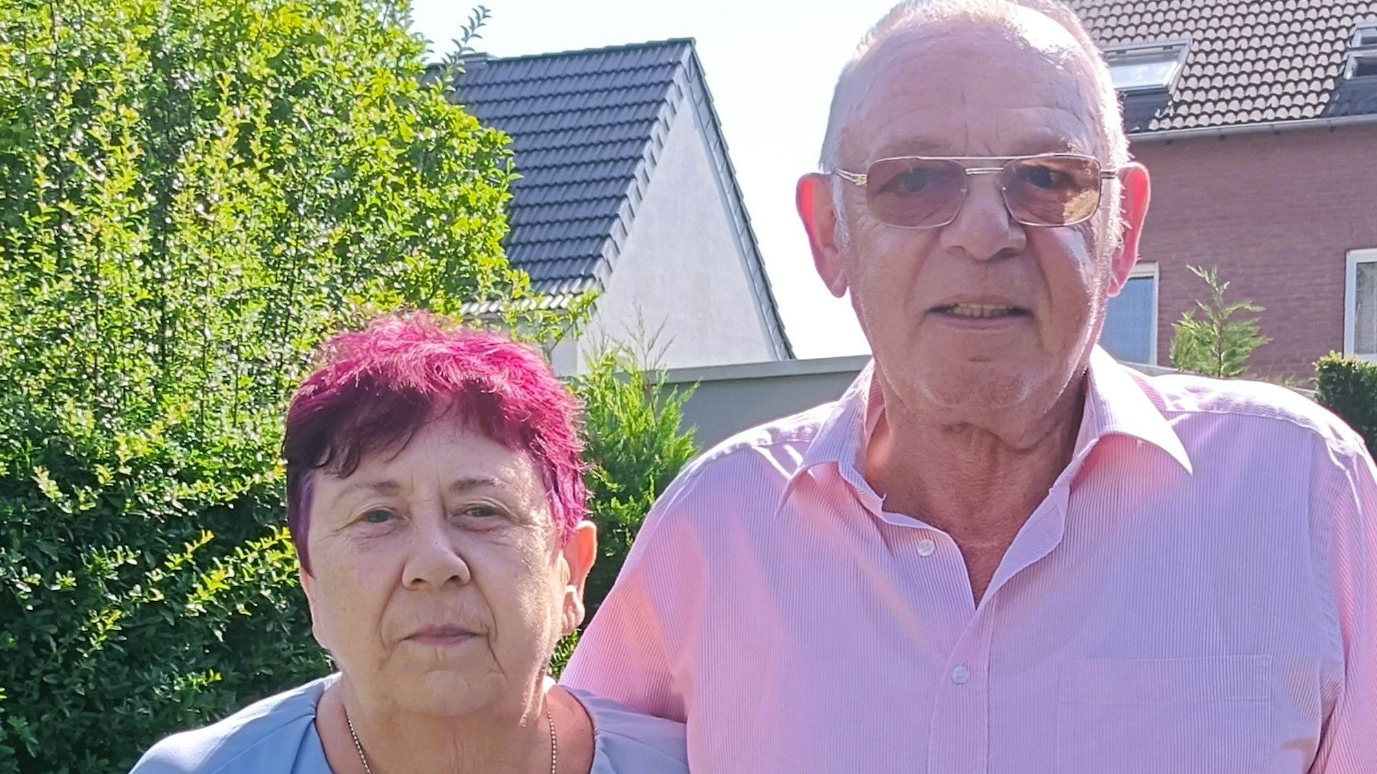 Eine Frau und ein Mann stehen Arm in Arm in einem Garten.