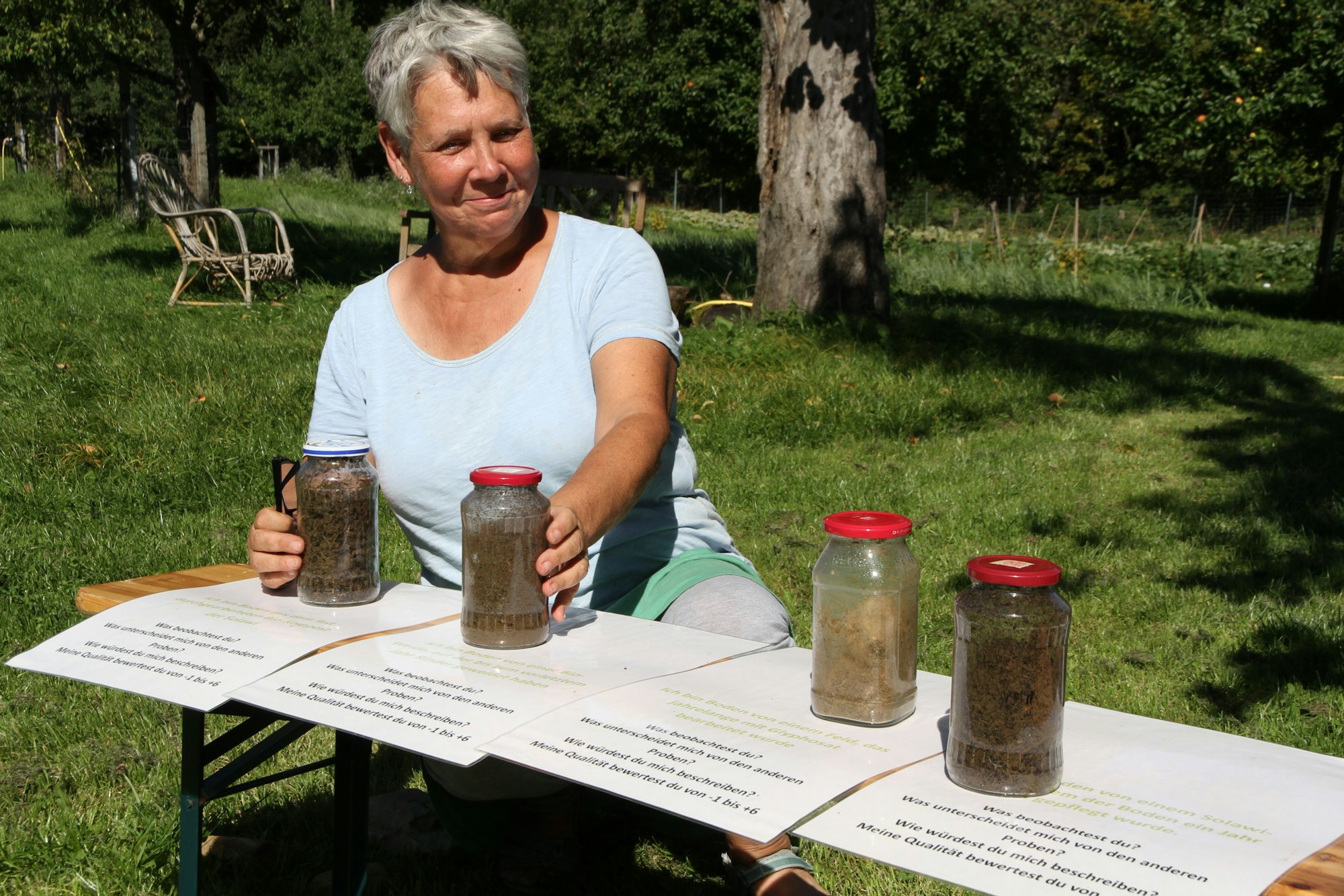 Sabine Müller, Vorständin der Genossenschaft eco:much - Solawi-Much eG mit verschiedenen Bodenproben in vier Einmachgläsern