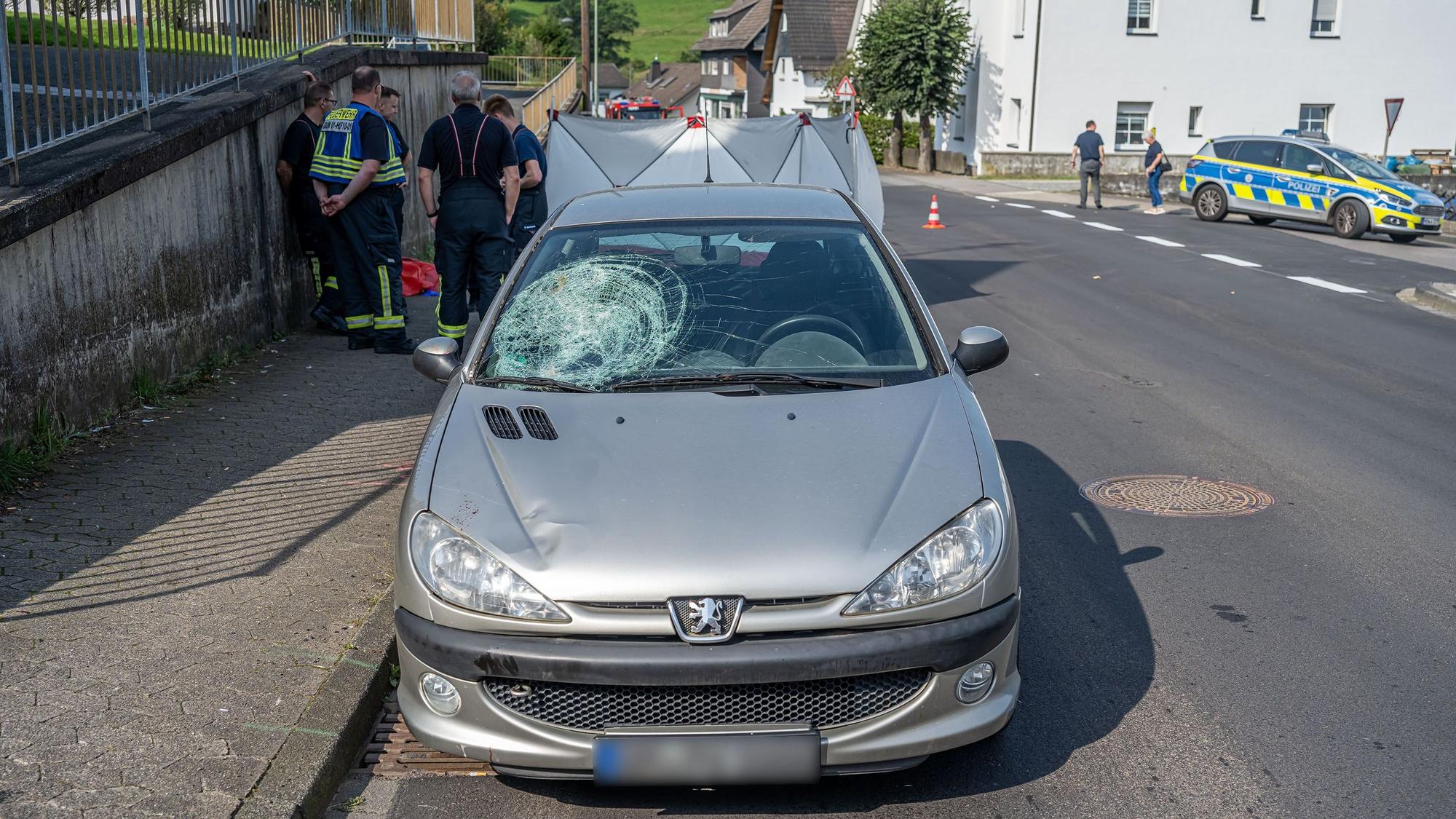 Ein Unfallwagen steht auf der Straße. Die Windschutzscheibe ist auf einer Seite eingedrückt.