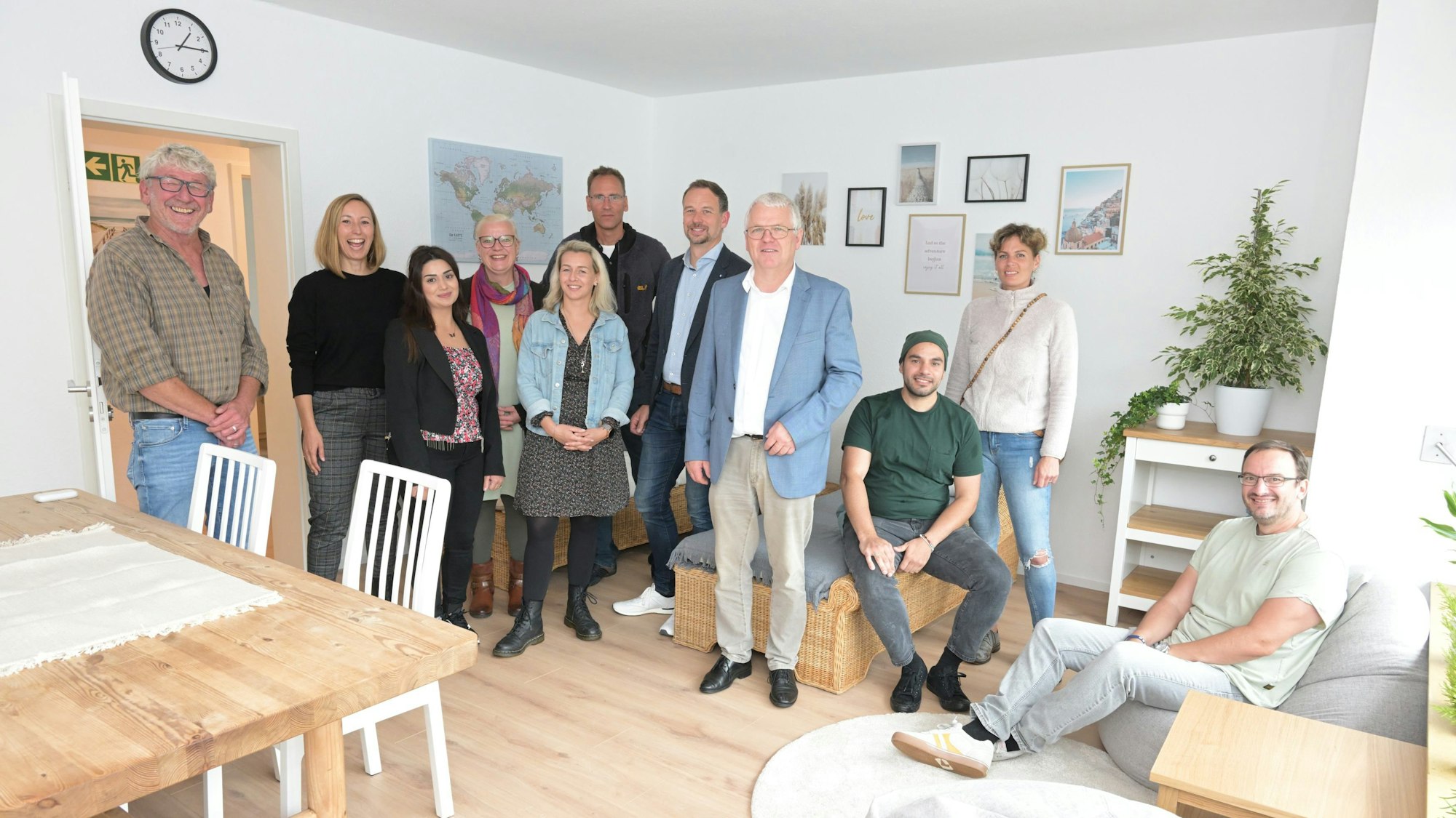 Elf Menschen stehen in einem hell eingerichteten Wohnraum in Kürten-Broich, der von einer Wohngruppe genutzt werden soll.