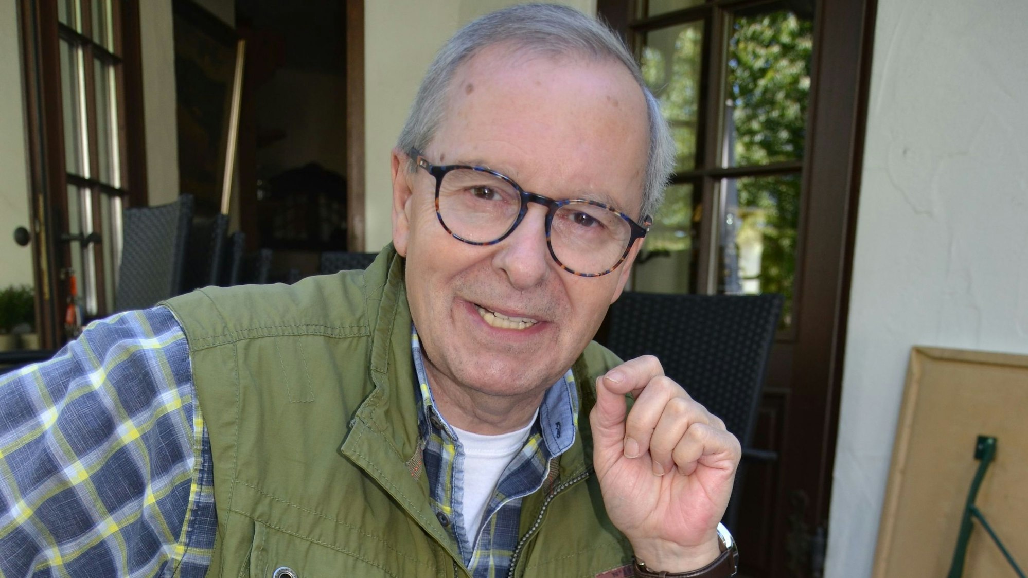 Günter Allmann sitzt in Reichshof-Hespert an einem Tisch und zeigt Bilder seiner Koch-Stationen.