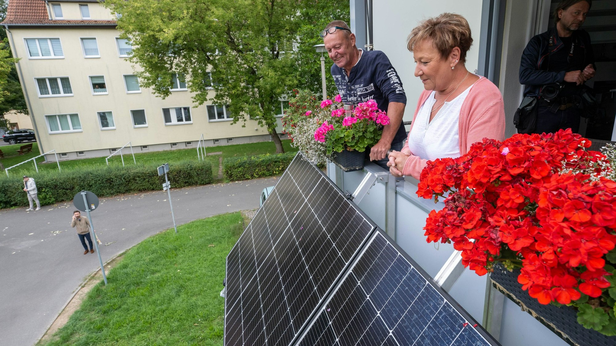Zwei Mieter blicken über die Module ihres neuen Balkonkraftwerkes am Balkon ihrer Wohnung.
