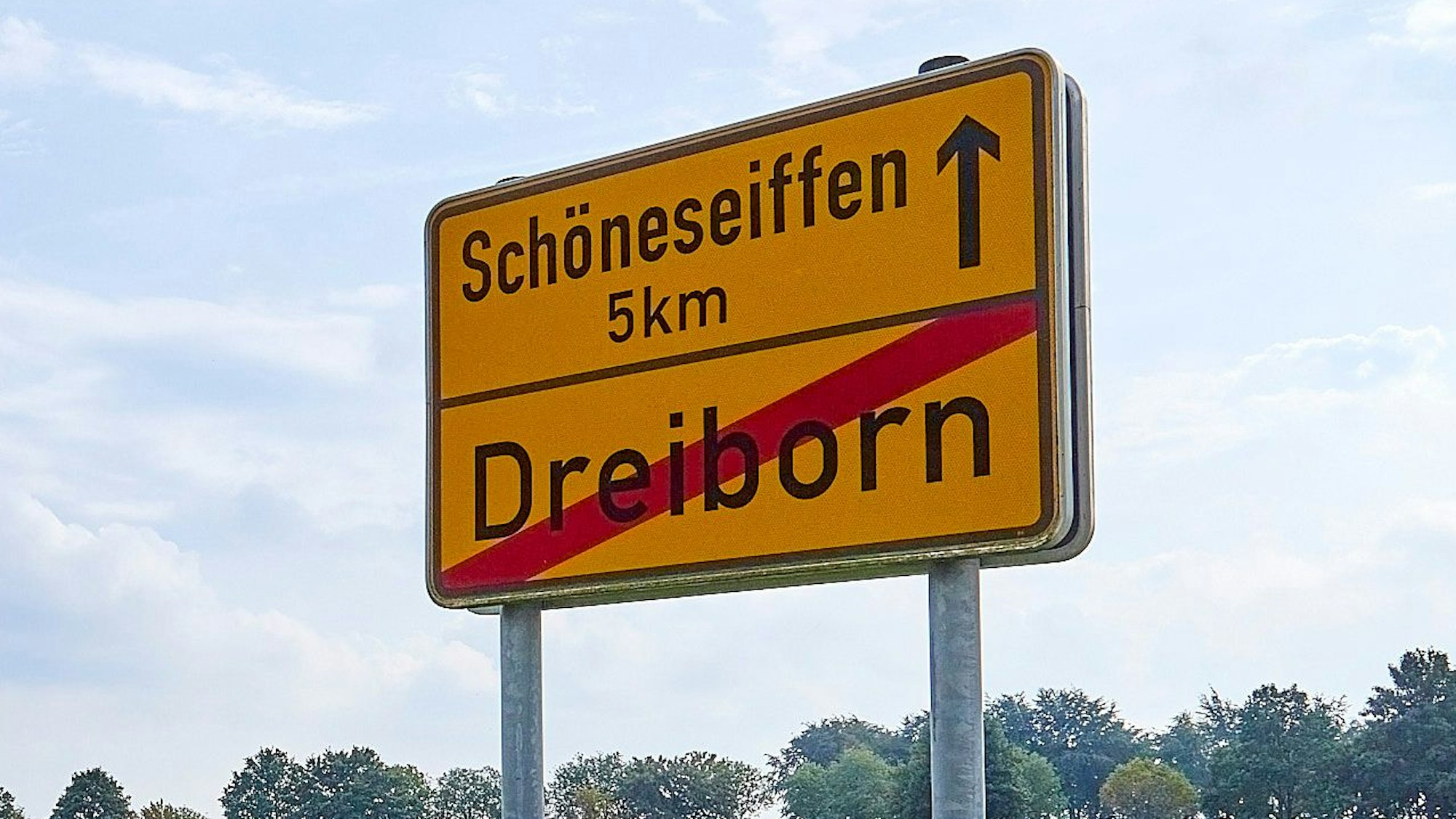 Das Bild zeigt das Schild am Ortsausgang von Dreiborn mit dem Hinweis, dass es fünf Kilometer bis zum Nachbarort Schöneseiffen sind.