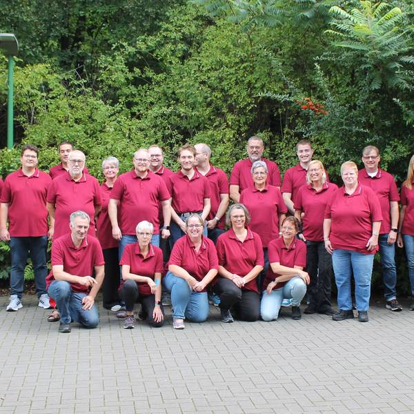 Rund 20 Mitglieder des Musikvereins Loope posieren in roten Polohemden.